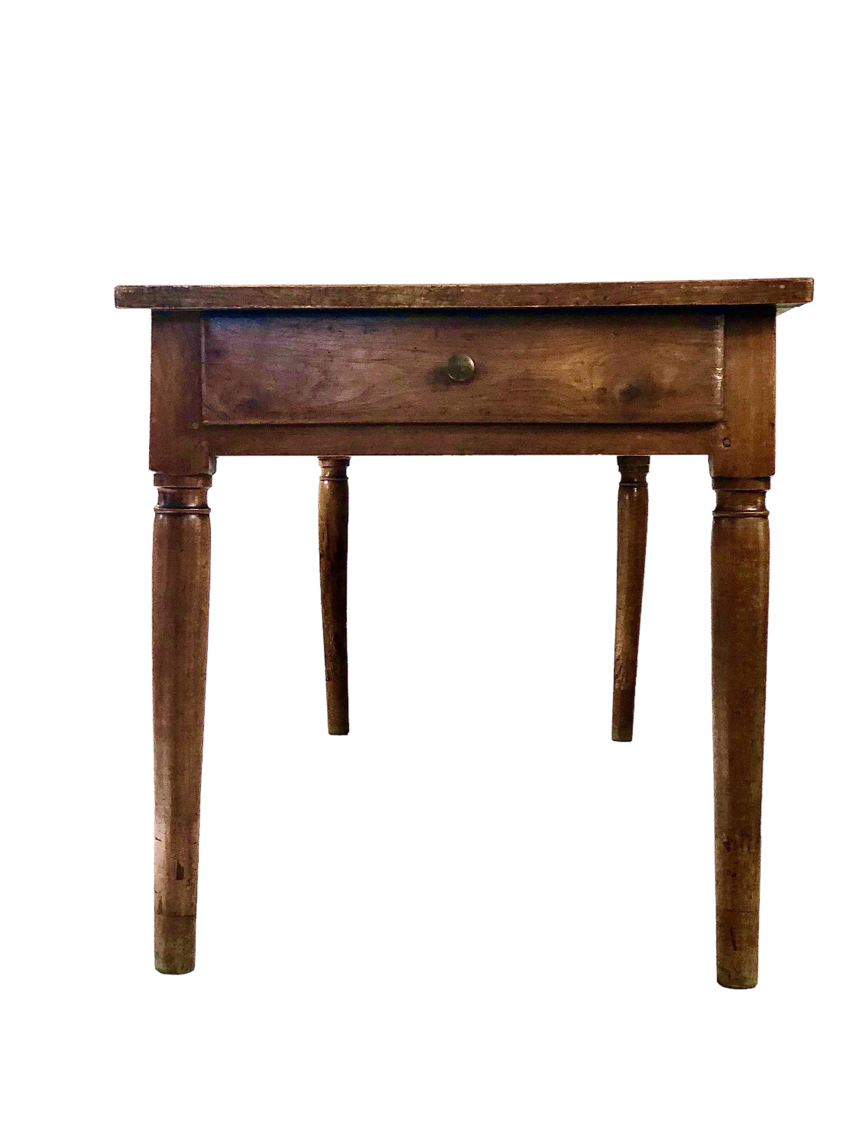 This authentic French farmhouse table features a solid rectangular top, supported by four turned legs. A nice patina and a desirable age wear are adding to its character and charm. The frieze has two extra-long storage drawers. It will seat 8 people