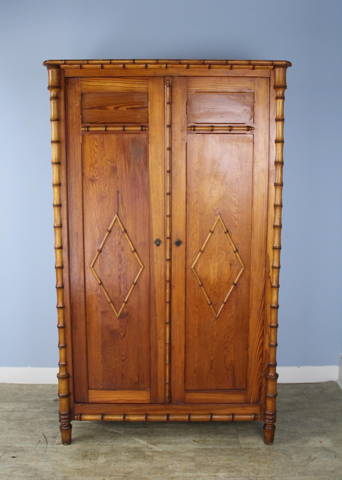 A small honey colored faux bamboo food cupboard or armoire from France. The piece boasts three shelves, removable but not adjustable, and already equipped to accommodate a clothes hanging rod.. The cornice and door features beautifully fashioned