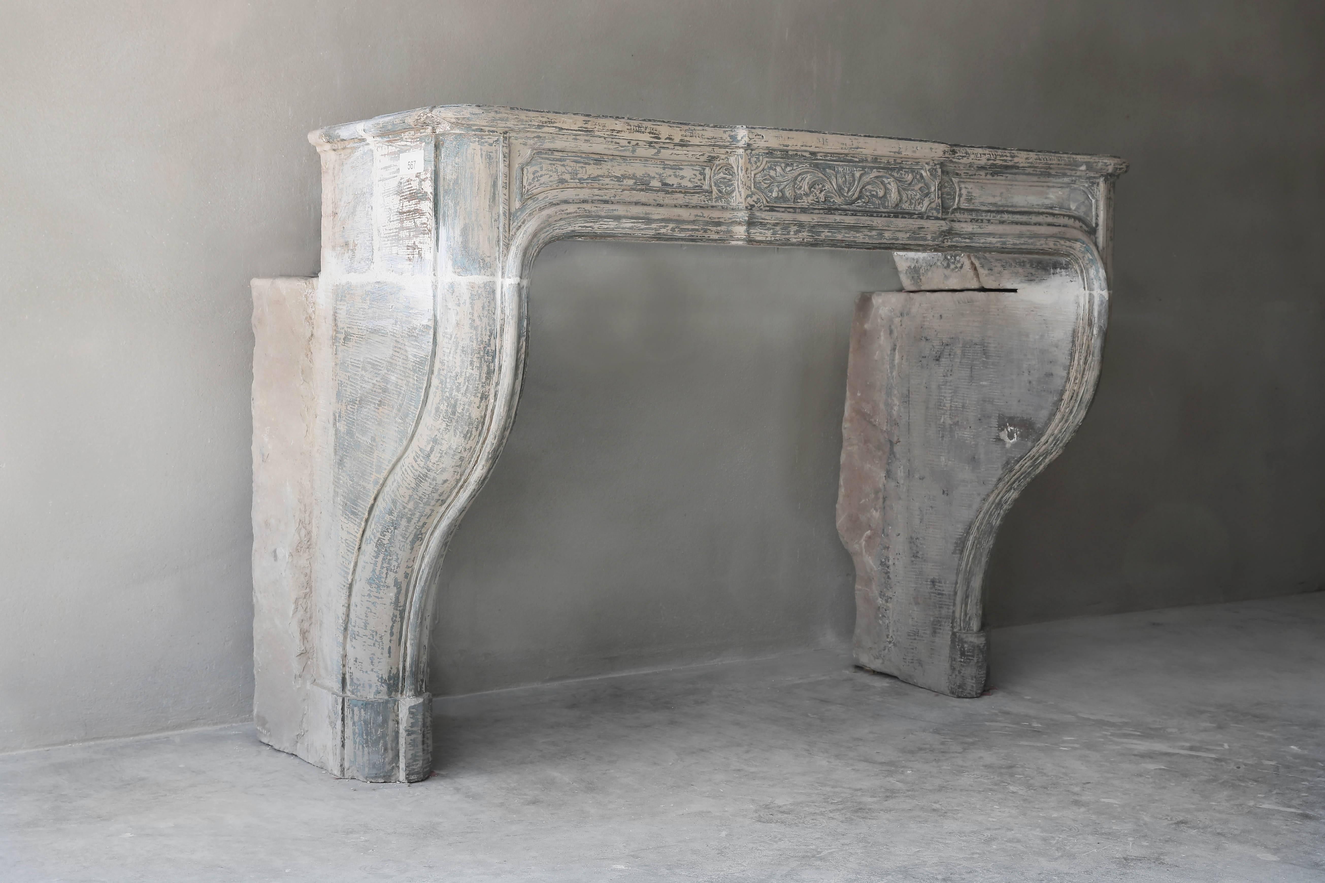 A very nice antique limestone of French limestone. The fireplace has a decorated front part and slightly curved legs. It's from the 18th century in the style of King Louis XIV. The fireplace is in the right proportions and is a very nice one in our