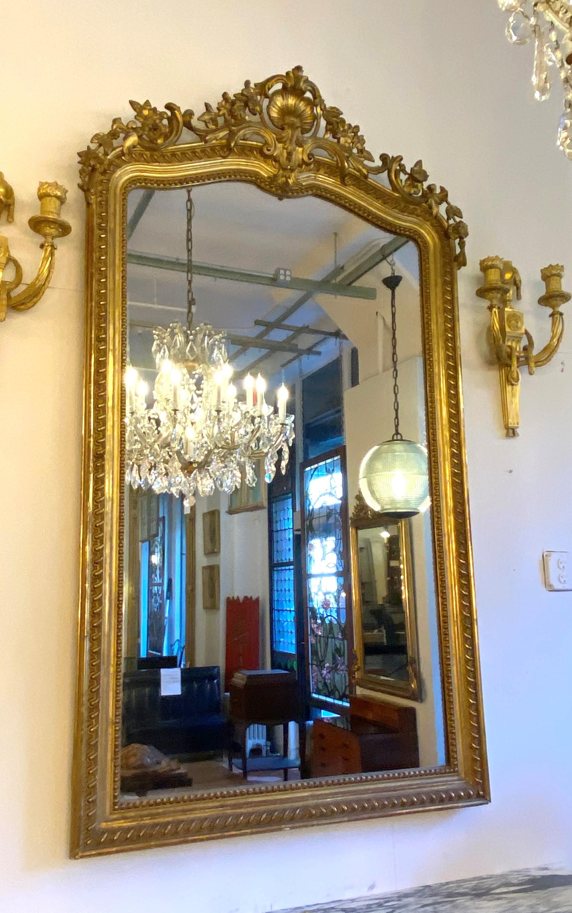 20th century Ornate antique French over mantel mirror. Gilt frame with hand carved wood and gesso. Design features shells, floral details, beads, flourishes and flowers. Please note, this item is located in one of our NYC locations.