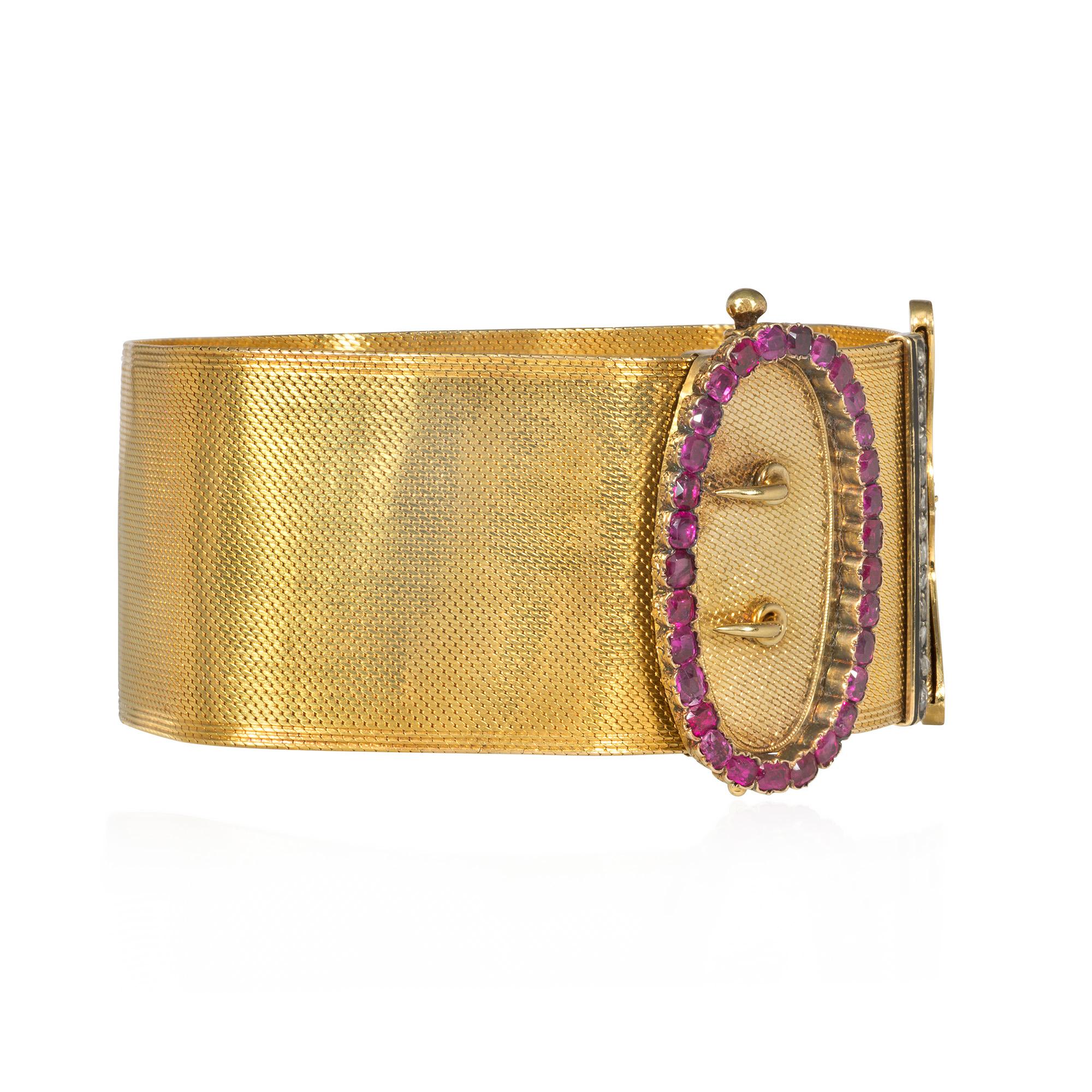 An antique woven gold jarretière slide bracelet designed as a buckled garter with cushion-cut ruby and rose-diamond fasteners and a scalloped terminal with black enamel Greek key decoration, in 18k. France

Slide design allows it to fit various size