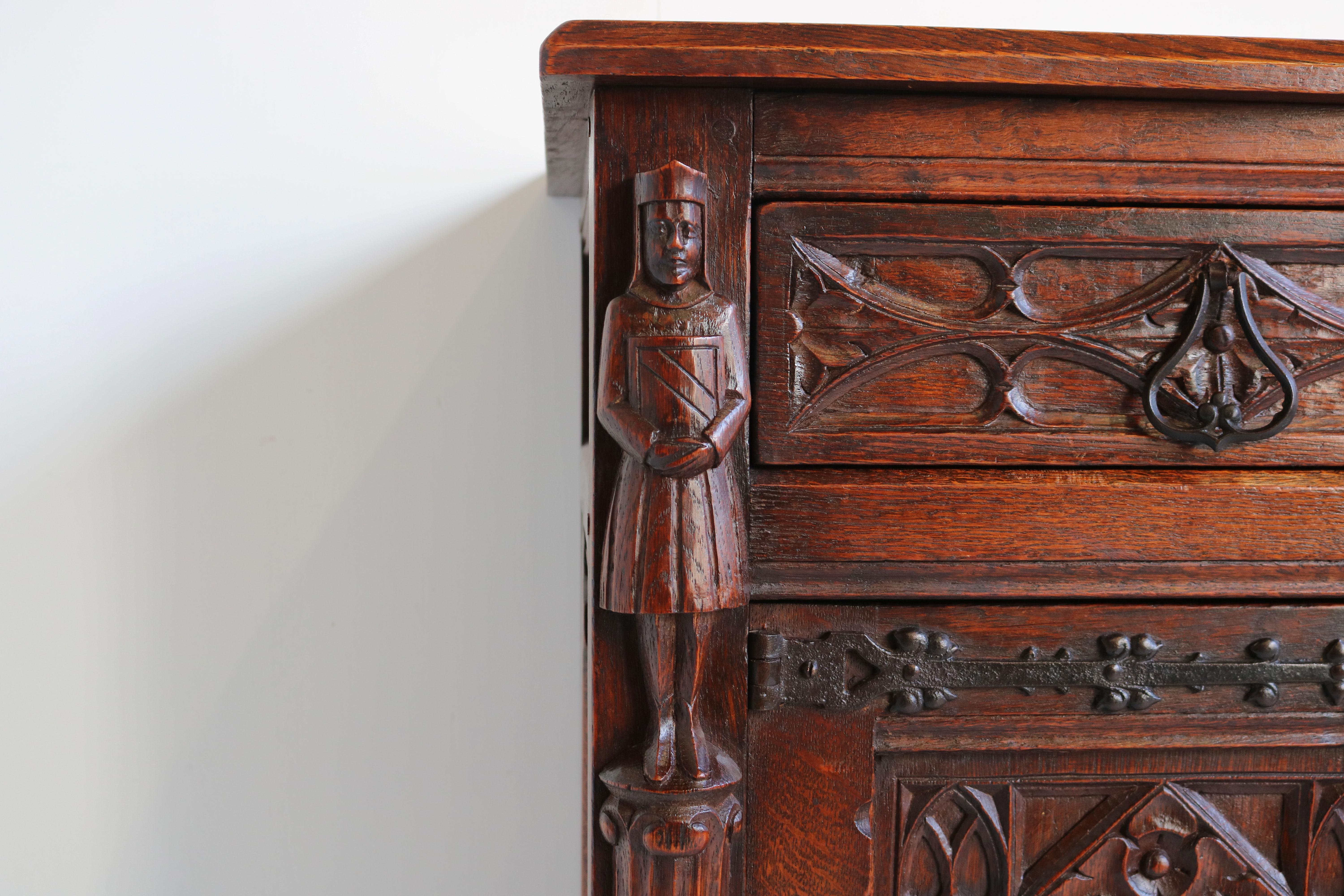 Gorgeous & practical ! This Antique French Gothic Revival Cabinet / Small credenza from the 1920s. 
Made out of hand carved European oak , with marvelous gothic details such as Knights & Cathedral arches. 
Great sturdy quality piece , with plenty