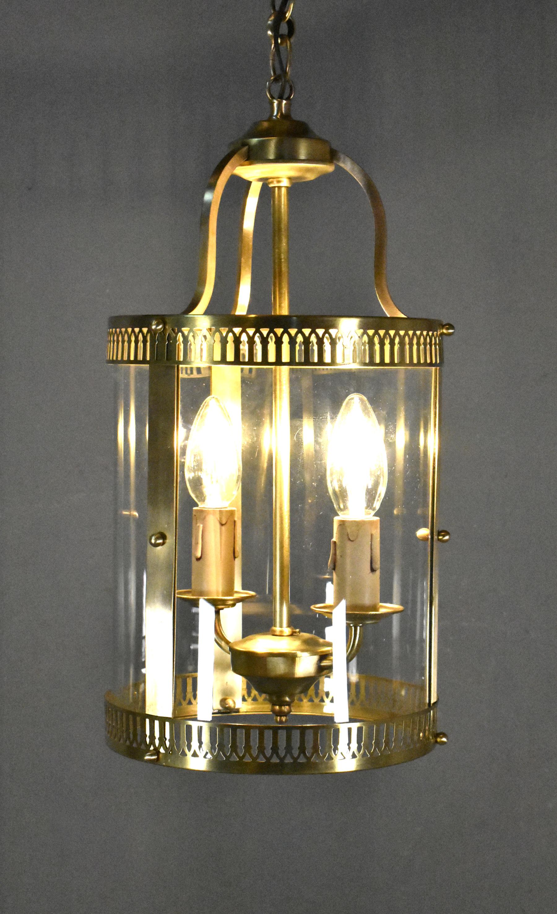 French Antique Hall Lantern in Brass 

An attractive round hall lantern featuring pierced brass continuous rings at the top and bottom that hold three curved clear glass panels in the centre. 

Descending from the polished ceiling rose there is a