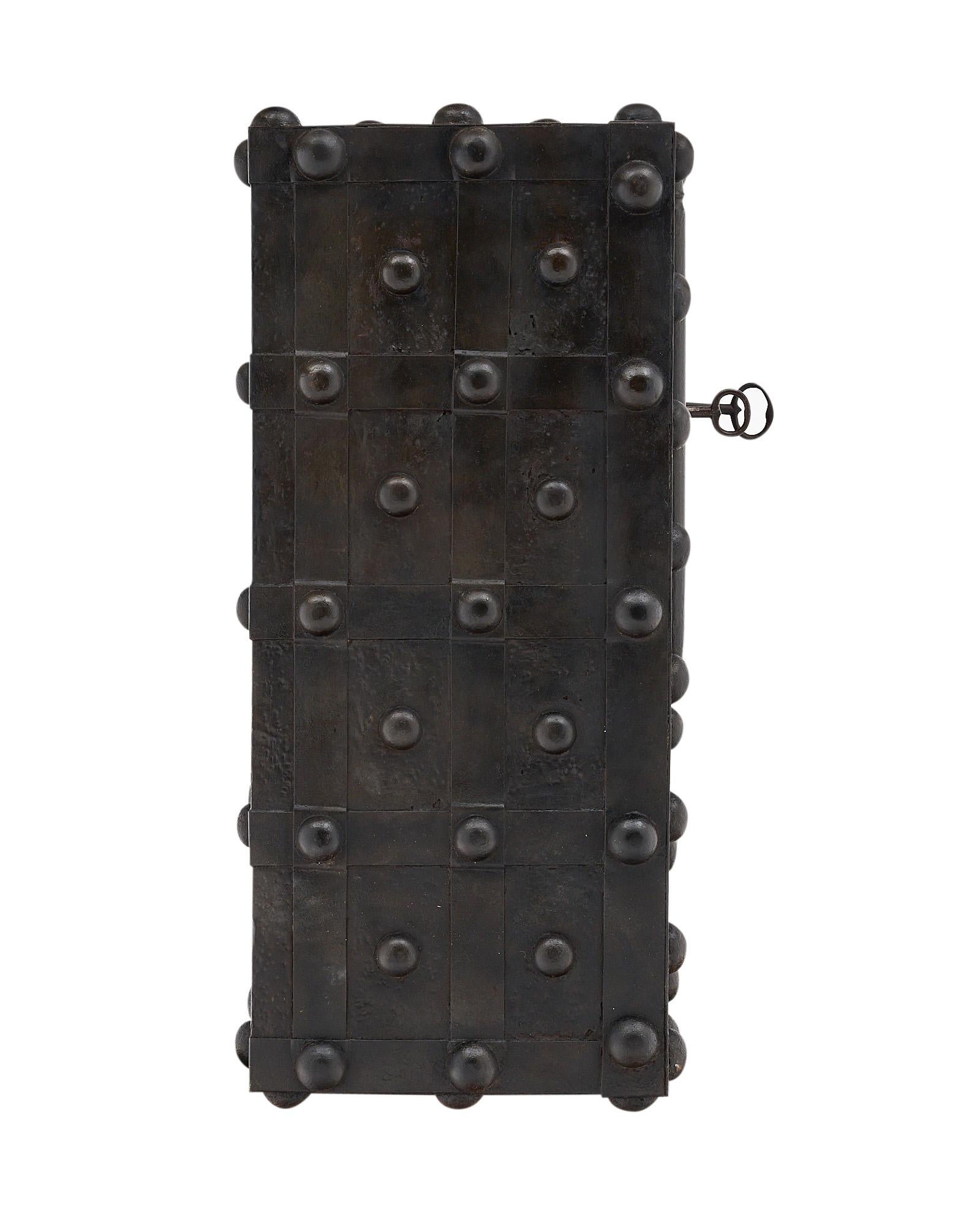 The wrought iron safe is decorated with nail head motifs on all four sides and has an all-original; working mechanism. The front door features two large hinges on the sides. The inside opens to reveal an amazing lock mechanism with three keys and a