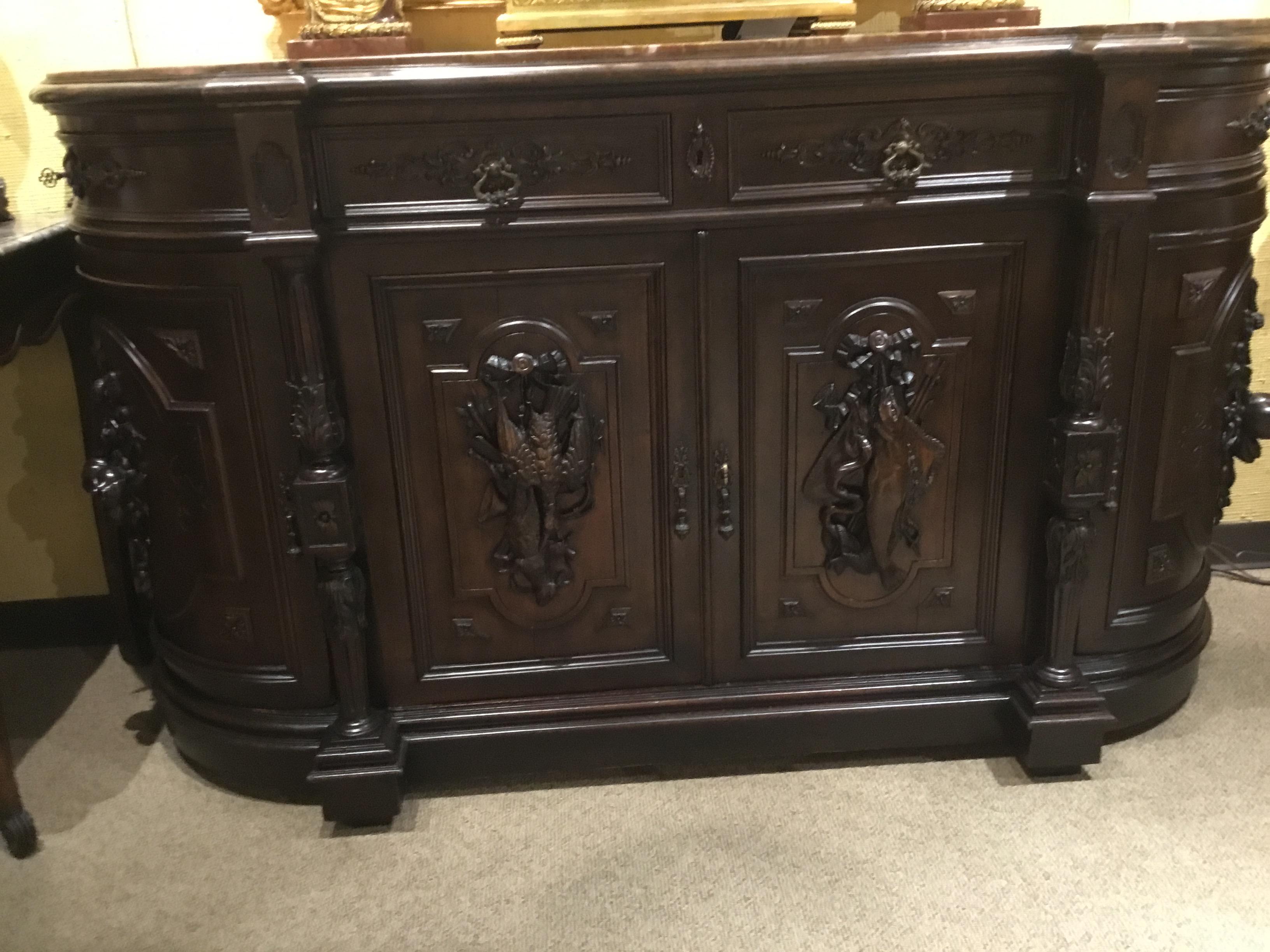 Handsome exquisitely carved hunt cabinet, hand carved with fish and fowl, fruit and nuts.
The cabinet is gracefully curved with four doors which exhibit a Black Forest type carving.
Four drawers open below the marble top. Four reeded and carved