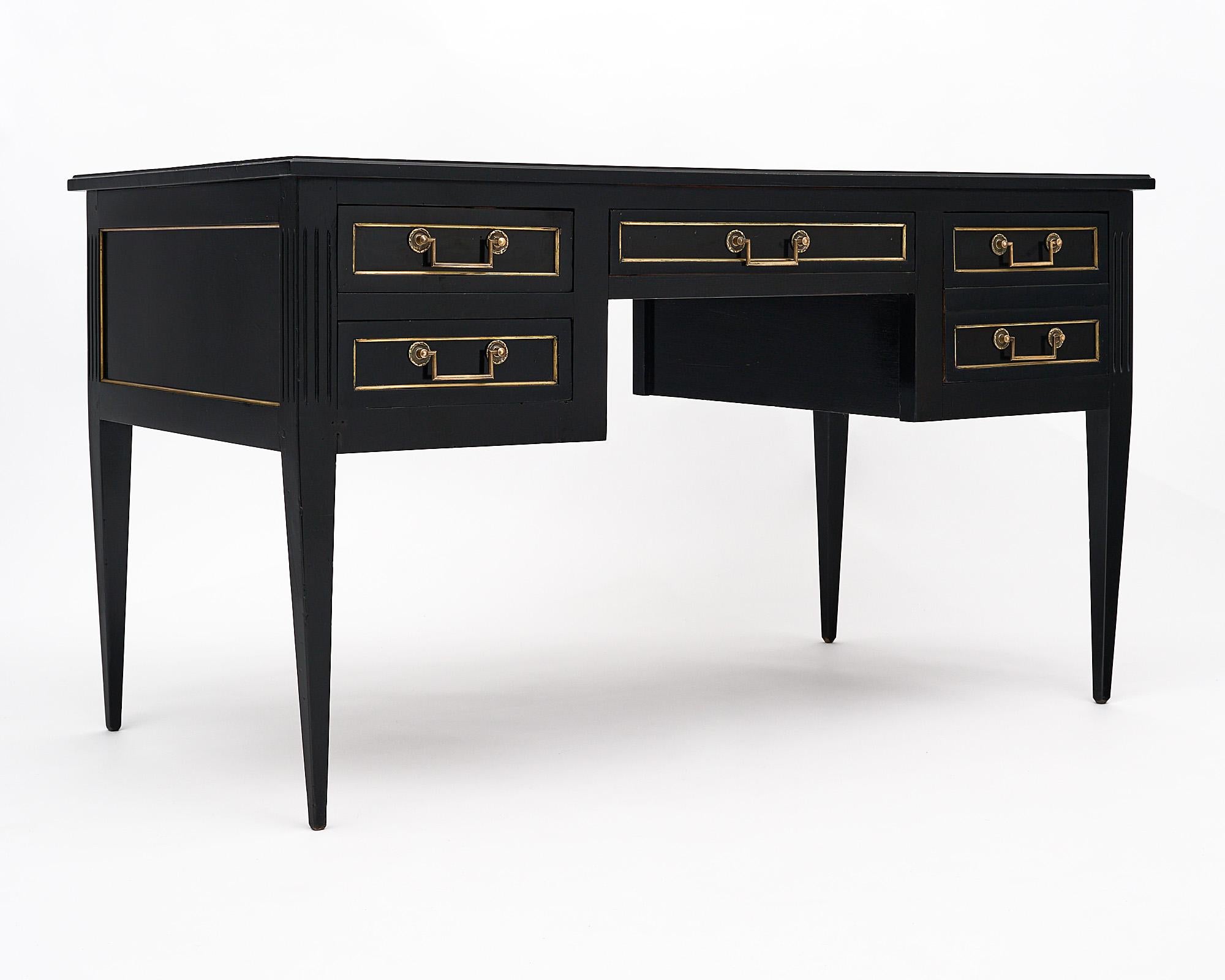 Desk; French; in the Louis XVI style made of ebonized Mahogany that has been finished in a lustrous museum quality French polish. This work table boasts a gilt embossed brown leather top and four dovetailed drawers. The original hardware and gilt