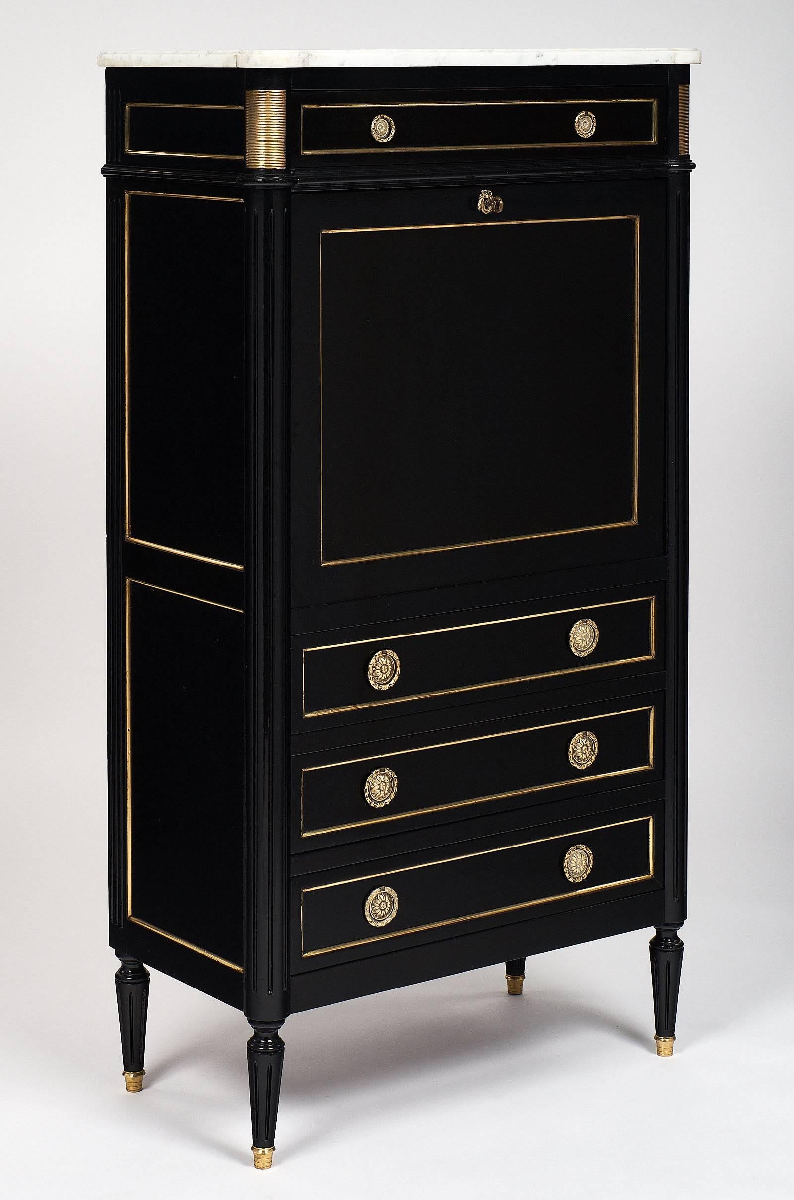 Antique mahogany “Secrétaire” finished with a lustrous ebonized French polish, Carrara marble top, and gilded trims throughout. This Louis XVI Style French antique secretary desk has three dovetailed drawers with their finely cast hardware, and a