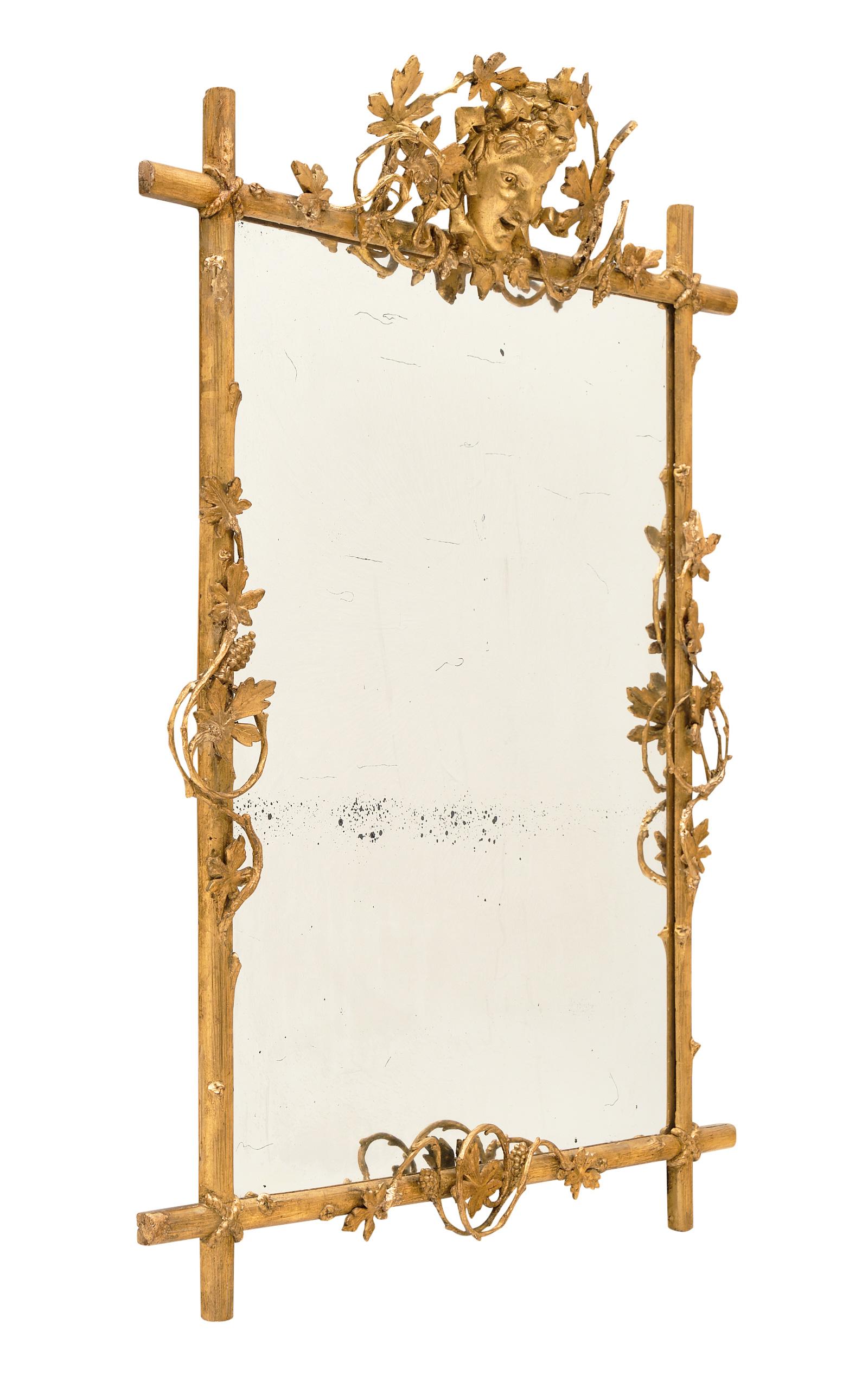 Antique French mirror with Bacchus fronton. This piece has a 23-carat gold leafed, hand carved wood frame with a striking fronton featuring the mask of a young Bacchus, interlaced with bows, grape clusters, wine canes and branches. This unique