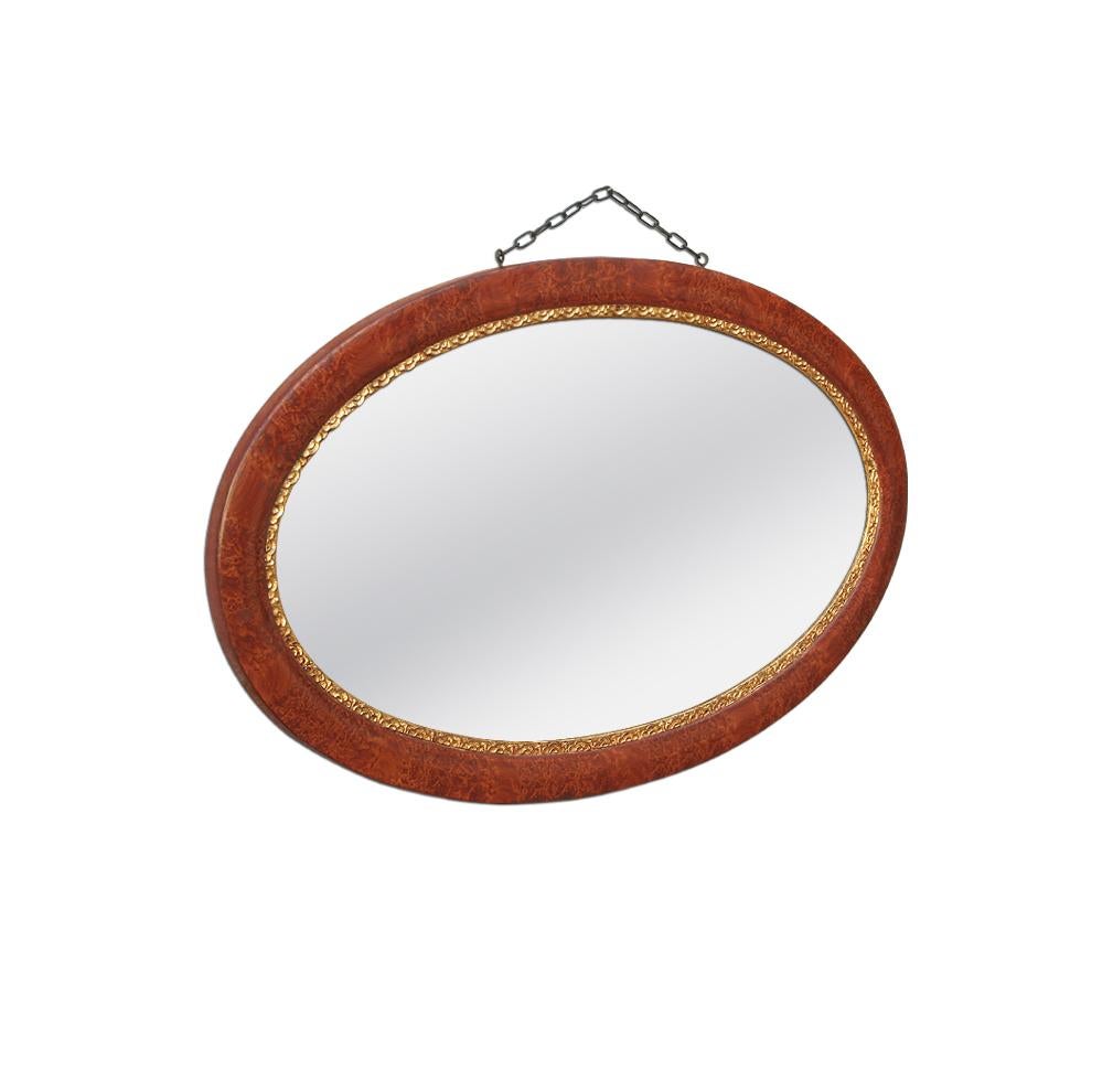 French oval mirror, early 20th century. Painting imitation wood and gilded floral ornaments framing the glass. Patina over time, origin color. Partial restored, re-gilding to the patinated leaf. Antique laminated wood back. Modern mirror glass.