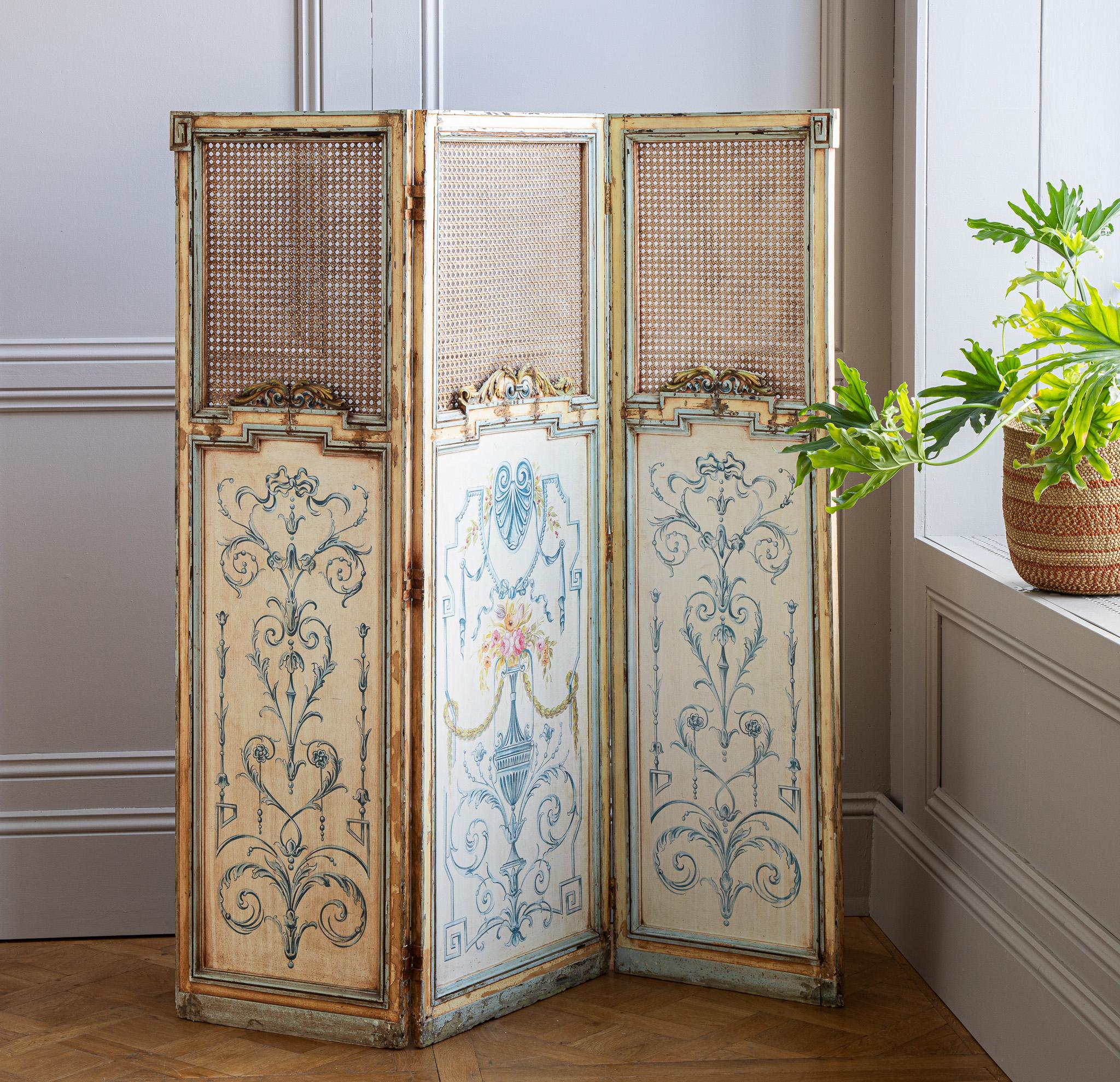1900s French Antique Paravent Screen in Louis XVI style. Originating from France, it showcases traditional cane work and hand-painted details. Suitable for subtle room separation or as a decorative element.