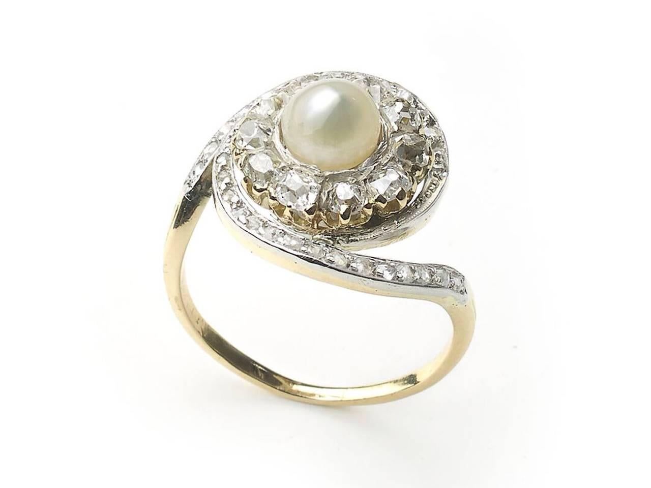 A French, antique, natural pearl ring, with a cluster surround of ten old-cut diamonds, in claw settings, with a swirling surround of rose-cut diamonds, in grain settings, with millegrain edges, set in silver-upon-gold, with a gold shank, with three