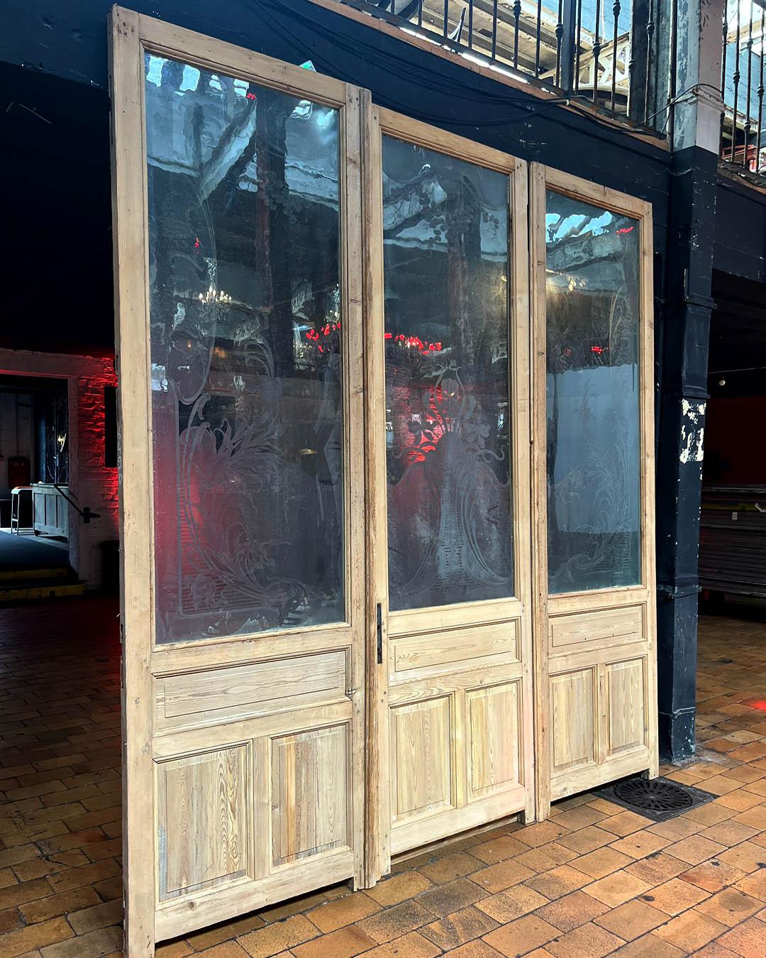 This stunning set of four folding shutters dates back to the early 20th century and showcases beautiful craftsmanship in solid wood. Each panel features delicate cut-out carvings of stylized floral and fleur-de-lis motifs, paired with louvered slats