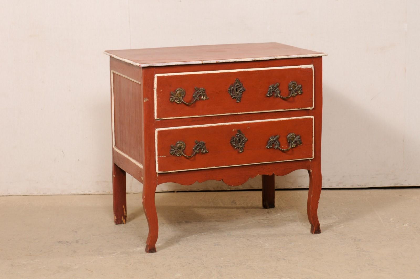 A French raised two-drawer chest, with its original finish, from the early 19th century. This antique commode from France features a rectangular-shaped top, whose edge slightly overhangs the case beneather, which houses a pair of vertically stacked