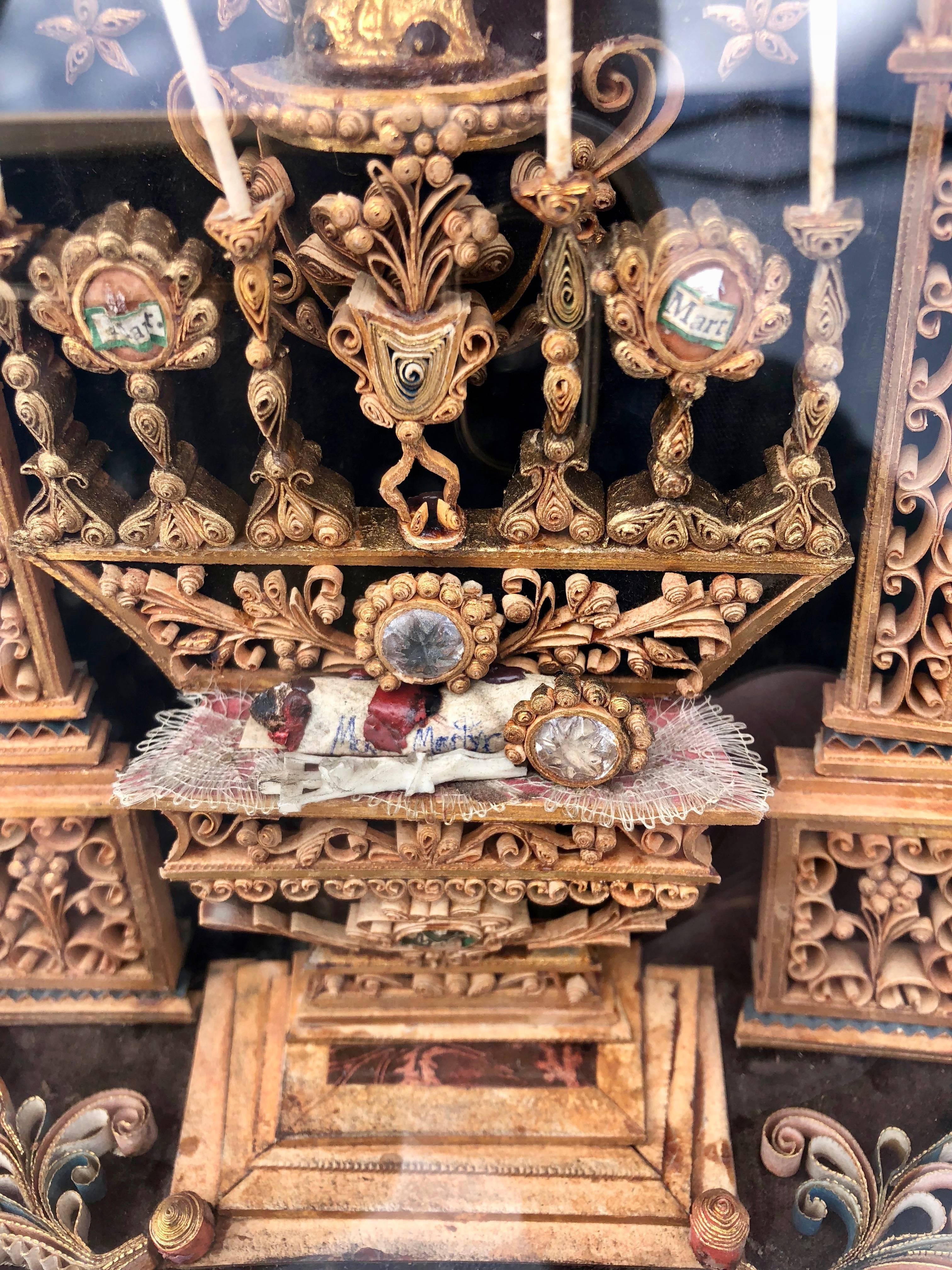 This is an absolutely gorgeous 18th century French reliquary which includes relics of four martyrs in a wooden pyramid shaped case with three glass panes. It features an altar with candles, a statue of Mary and infant Jesus and miniature