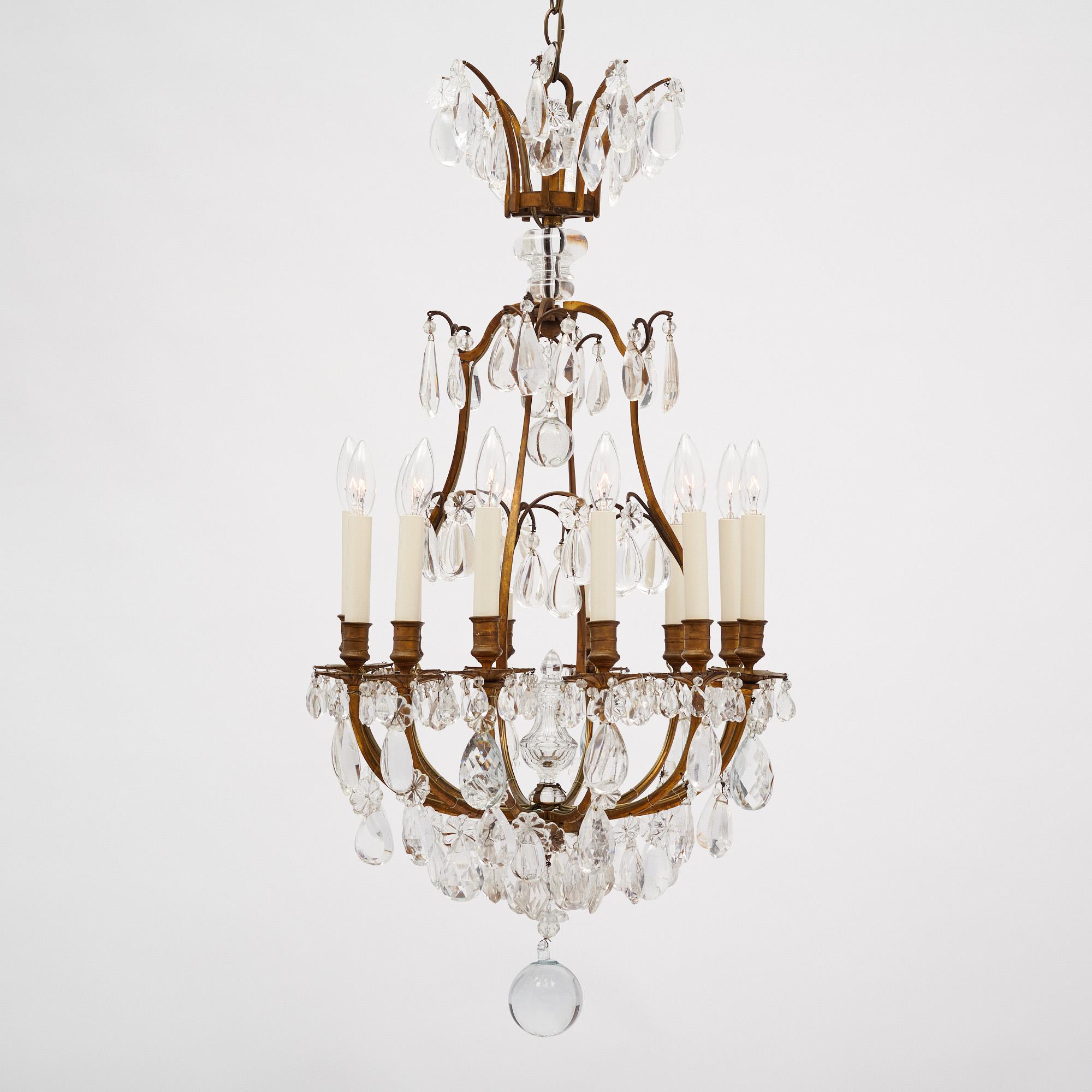 Lampadario francese realizzato in metallo ormolu con una ricca serie di cristalli di rocca. Include un grazioso terminale a sfera di cristallo e 12 bracci a candelabro. Questo apparecchio è stato cablato di recente per adattarsi agli standard