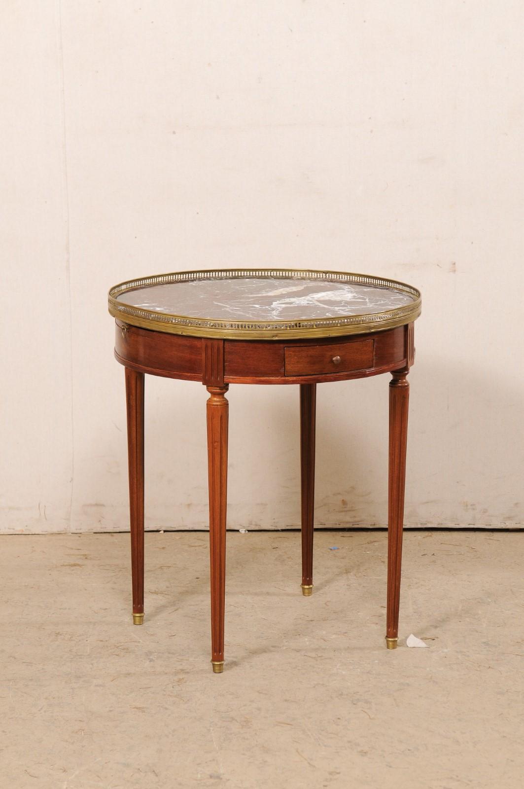 Französischer Beistelltisch aus Kirschholz mit Messing- und Marmorplatte aus dem frühen 20. Jahrhundert. Dieser antike Tisch aus Frankreich hat eine runde, abgeschrägte Steinplatte (in dunklen Wein-, Weiß-, Schwarz- und hellen Brauntönen), die von