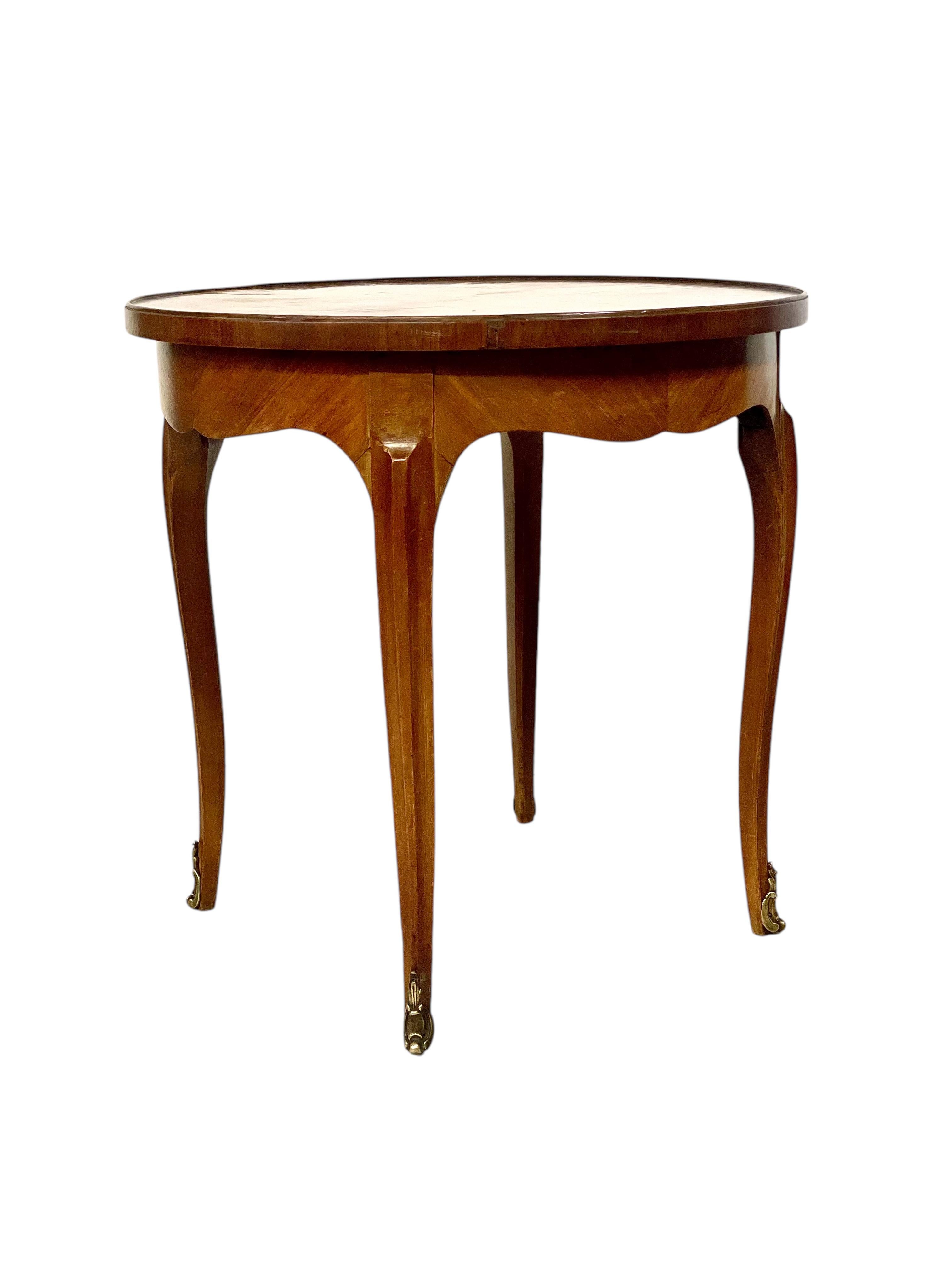 An elegant and very practical French antique salon table in rosewood veneer, dating from around the 1930s, and featuring a simple but effective marquetry decoration. The polished, circular top is quarter-veneered with a wide border, while the apron