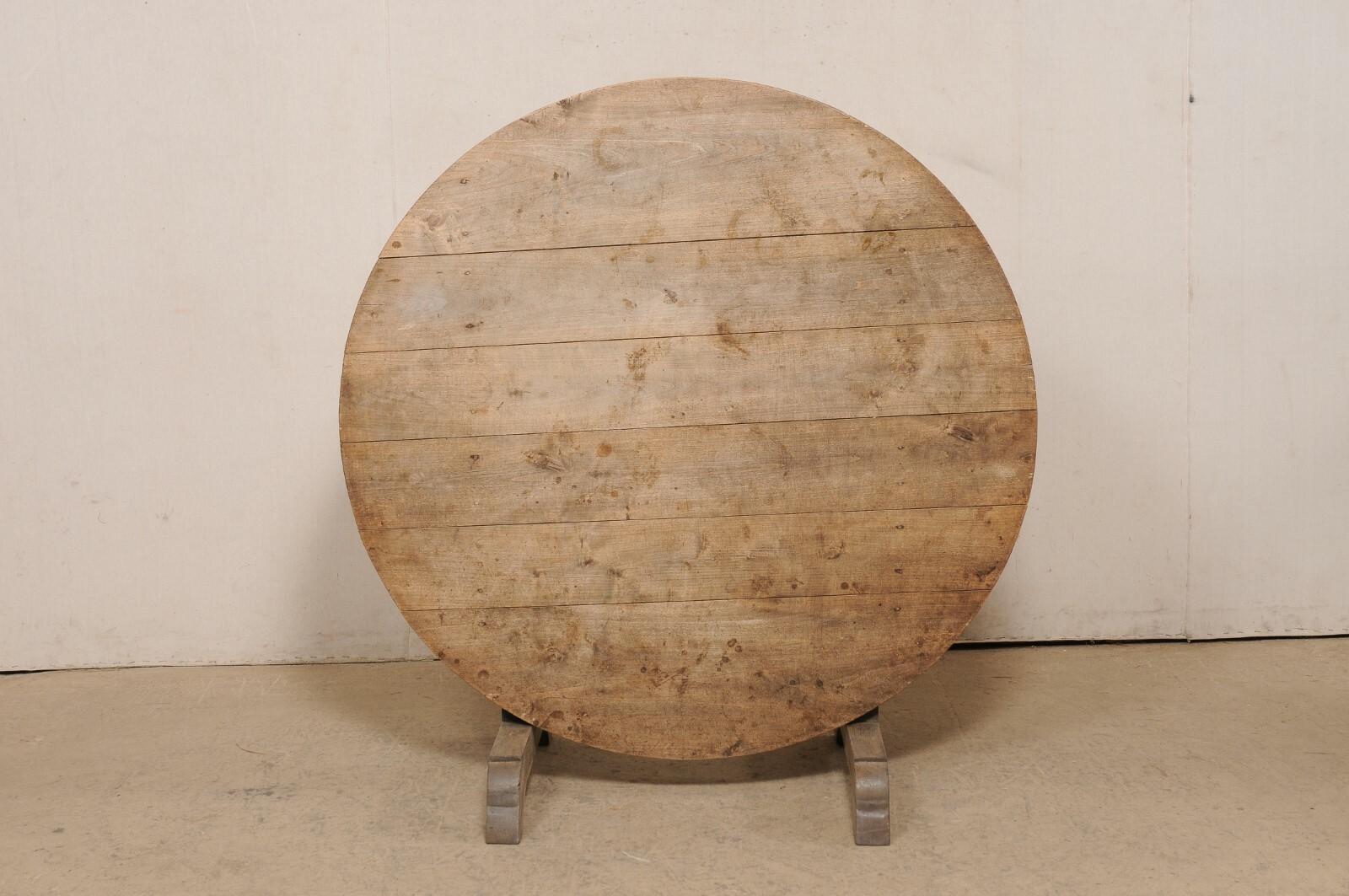 A French tilt-top wine tasting table from the late 19th century. This antique round-shaped table from France features a tilt top, which is the signature of wine tasting tables during this time, which is supported with a butterfly wedge, between a