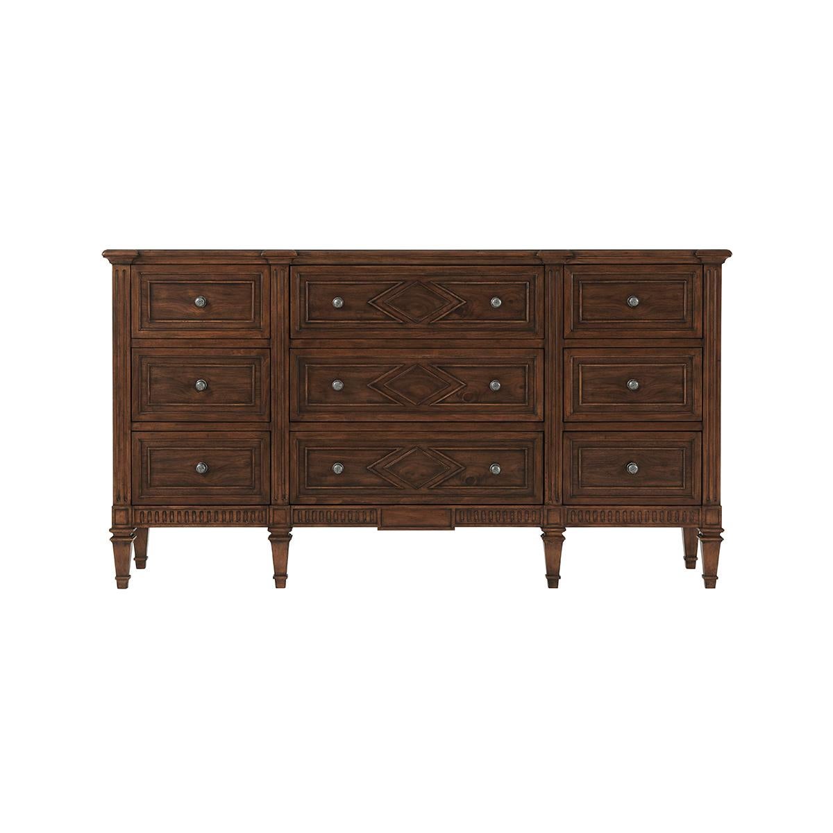 In a dark walnut finish with a molded edge rectangular top, nine paneled drawers with lozenge detailing motifs, antiqued pewter handles, with a fluted base and raised on square tapered legs. In the French Directoire style.

Dimensions: 70