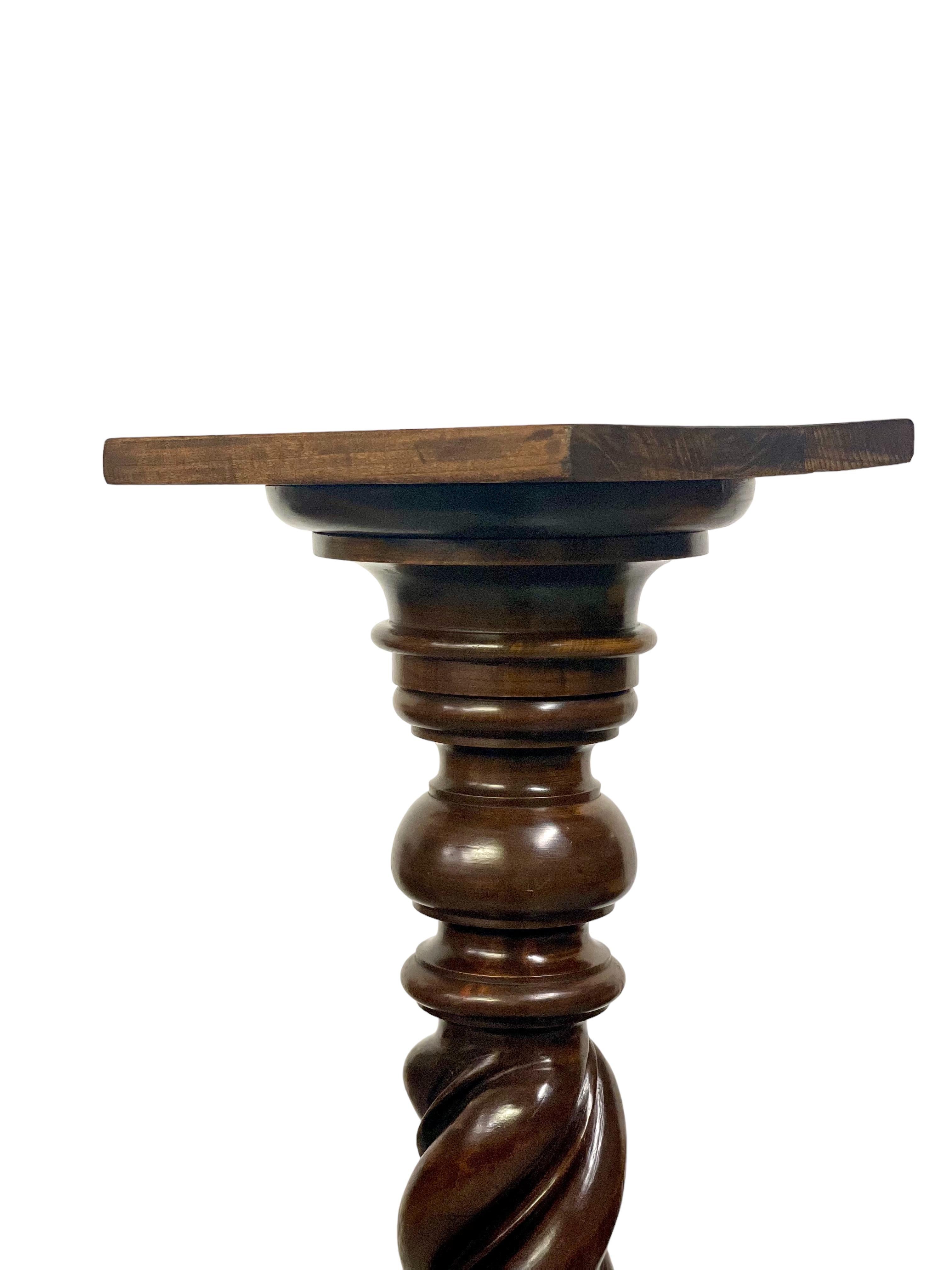 A beautiful antique wooden pedestal column, its body carved into an impressive twist, and featuring nicely turned upper and lower sections beneath a square display tray. The column sits atop a substantial, shaped square plinth, which provides