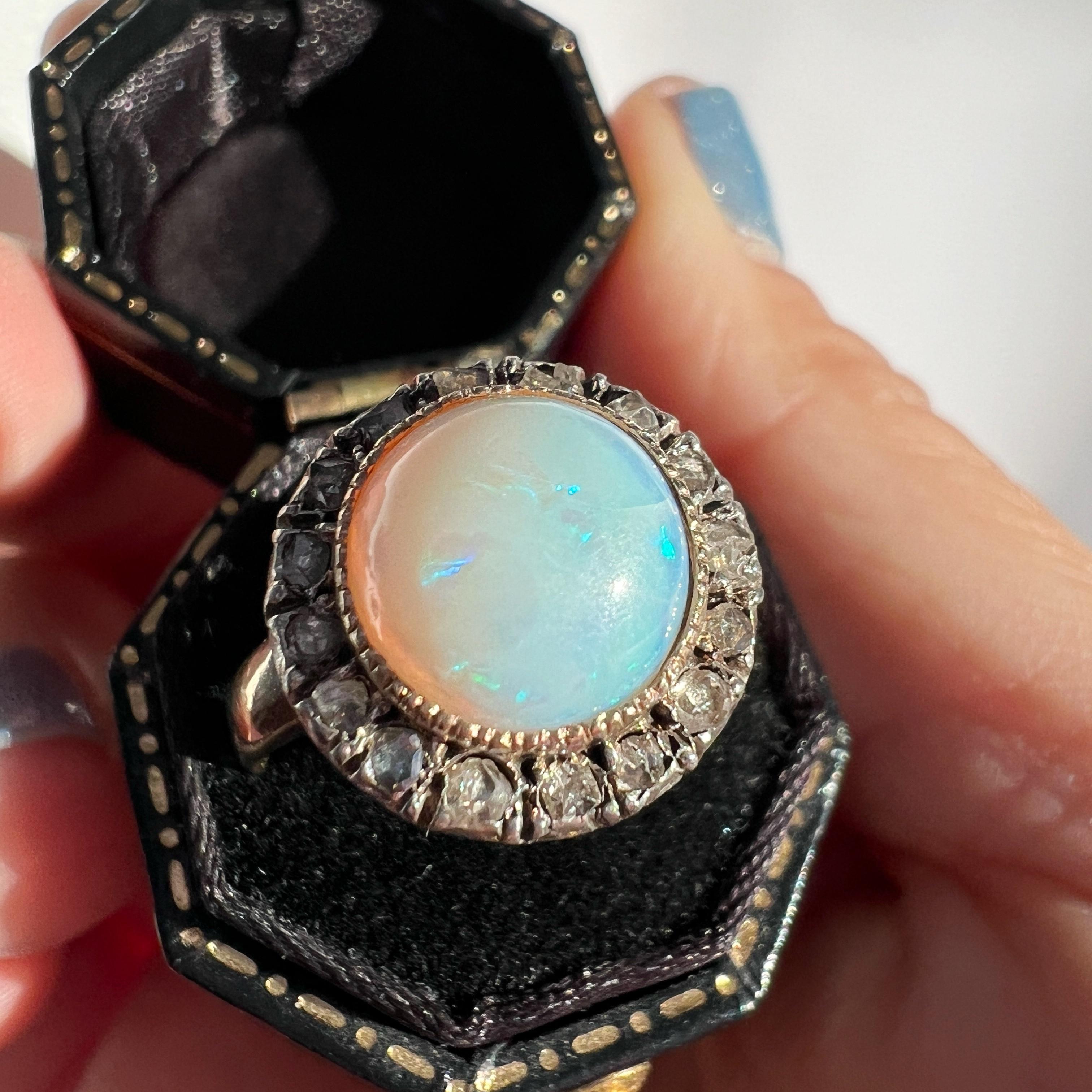 For sale an antique 18K gold ring made from the 19th century, the Victorian era. At its heart lies a captivating semi-transparent opal cabochon, measuring approximately 5mm in diameter. Encircling this magic gemstone is a delicate frame of 16