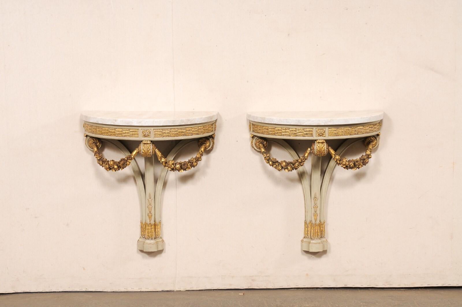 A French pair of carved-wood wall mounted consoles, with their original painted finish and new marble tops, from the early 20th century. This antique pair of console wall brackets from France have demi-shaped tops (a new addition of custom made Taj
