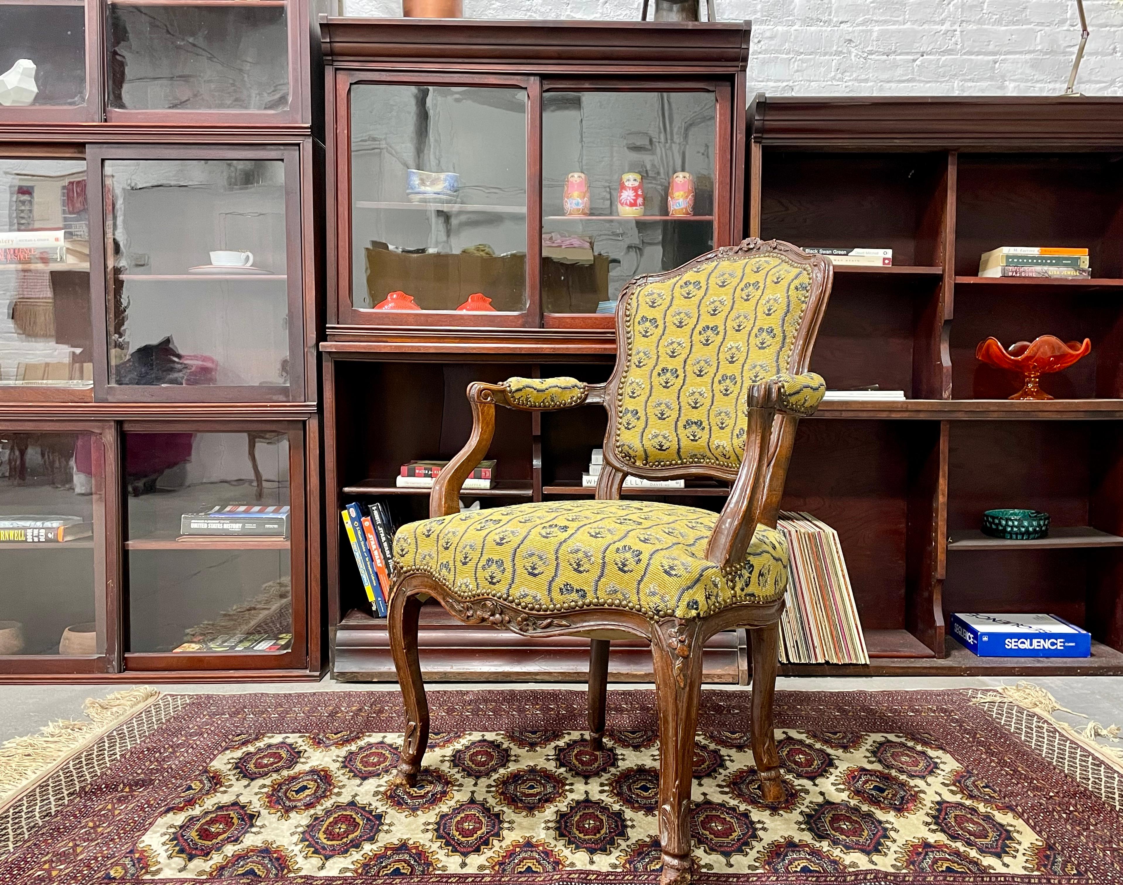 French Antique Walnut Louis XV Walnut Armchair featuring deep hand carved elegant flower and foliage designs. Made in France circa mid-1700’s. The upholstery is a lovely tapestry of yellow with blue patterned design. Nice antique condition with wear