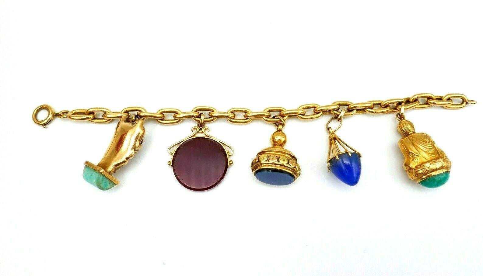 Antique French 18k yellow gold charm bracelet featuring five gemstone charms. 
Carved carnelian spinning charm; two-tone gold agate signet charm; cone chalcedony charm; Buddha with amazonite; Dragon Head with jade. Stamped with French