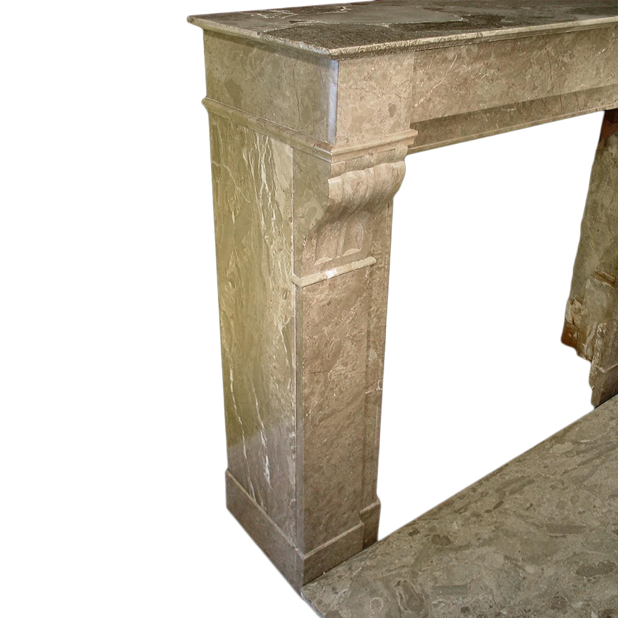 A wonderful French architectural marble fireplace mantel. The mantel legs are decorated with carved mouldings of fluted scrolls. The marble is in brown and off white veins. The top has a rectangular shelf. The mantel comes with its original marble