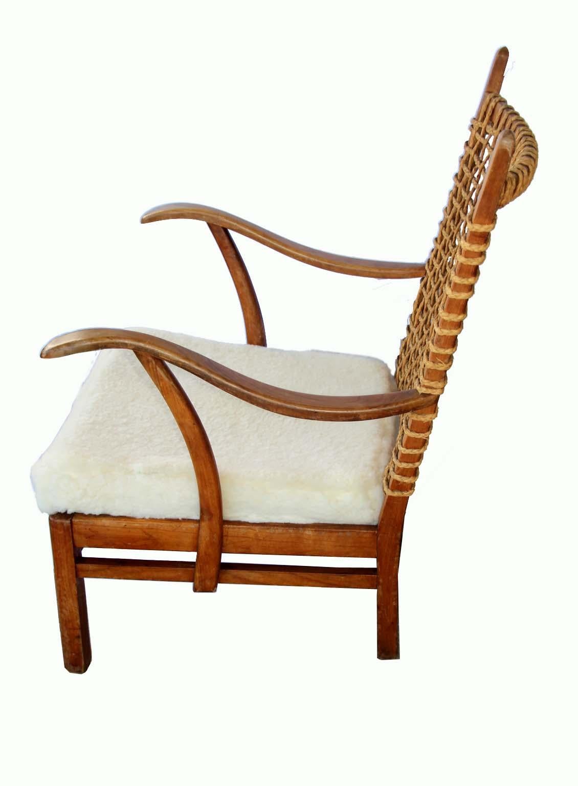 Unsigned Wood Armchair with a rope backing and soft lambskin seat(seat New cover). The lines are amazing and the patina and rope makes this chair Stand out as a really original and unique piece of furniture. Comfortable, stylish design brings warmth