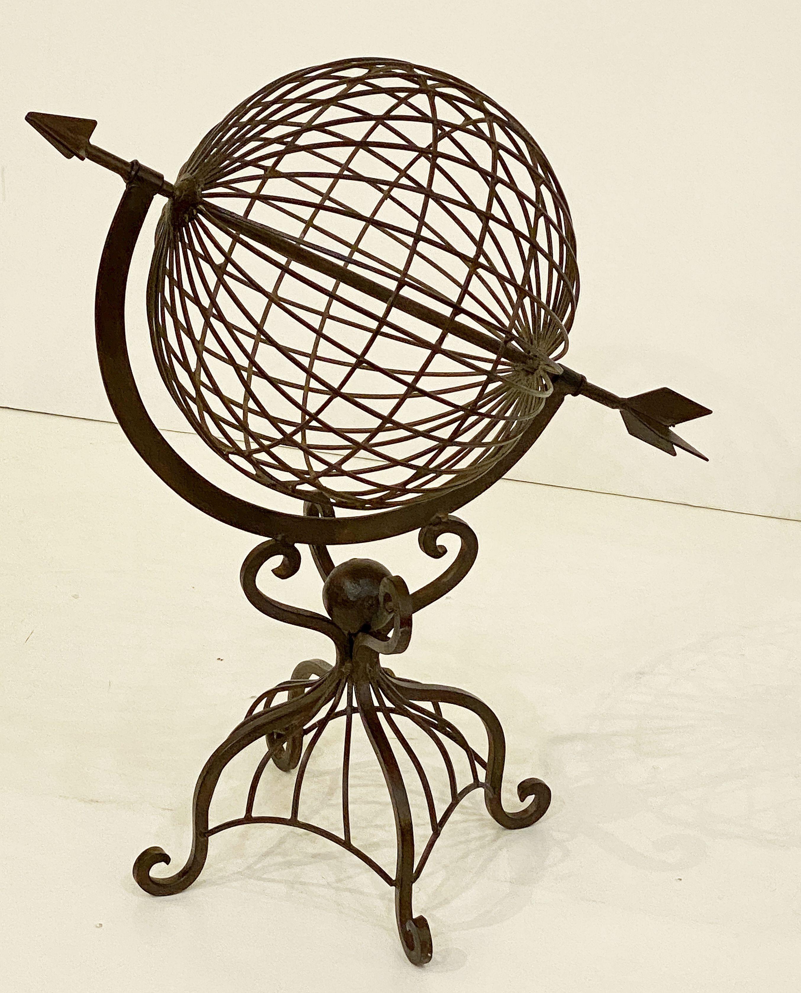 A fine French armillary sphere or decorative garden ornament of wrought iron featuring an arrow positioned in a globe mounted to a four-legged support stand.

Dimensions: H 23 1/2 inches x W 20 inches x D 12 inches

An armillary sphere is a