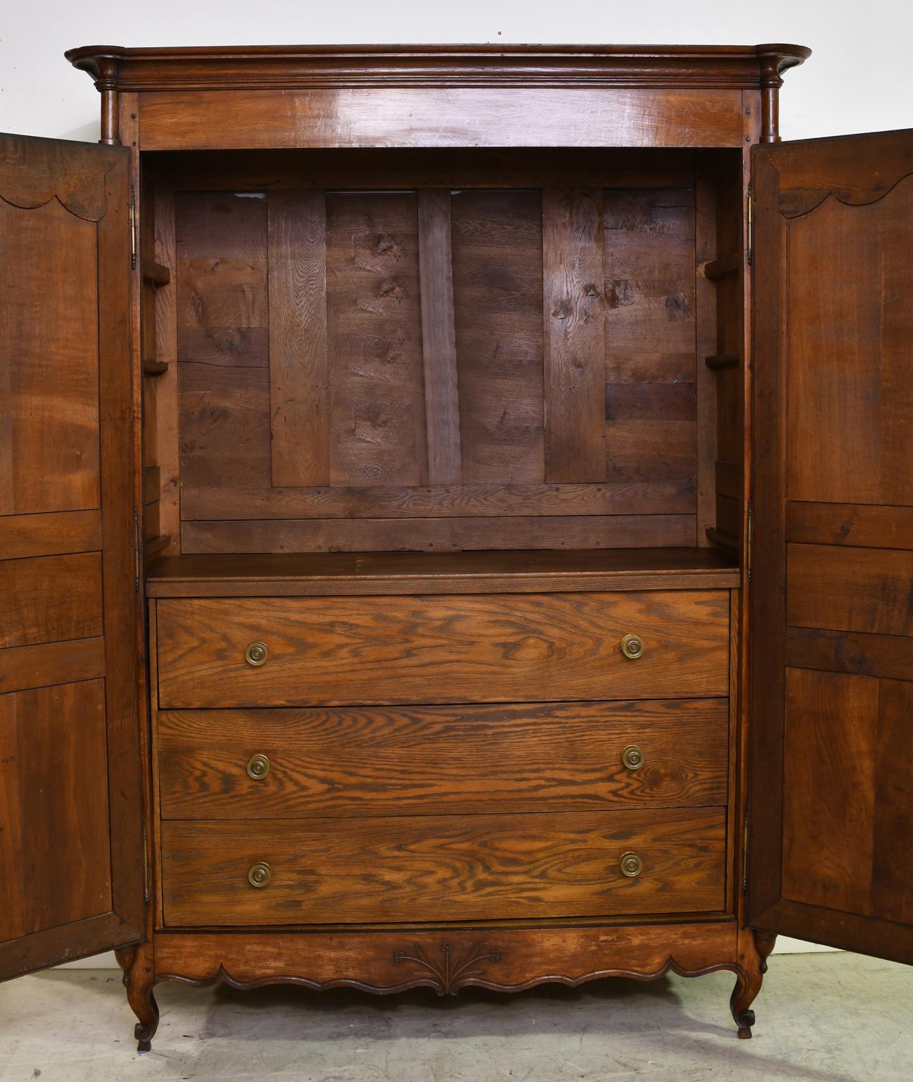 A French armoire, likely from the Empire period, in beautiful French oak with two doors opening to an interior offering three large storage drawers, also in oak, that were added in recent years to match the exterior. Armoire has turned columns with