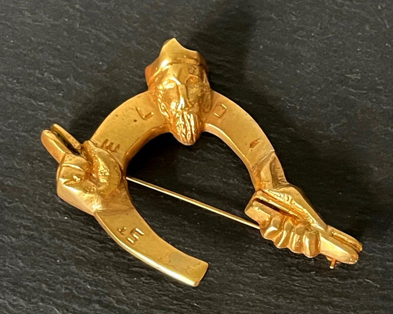 A rare bronze brooch St Eloi by Parisian art jeweler Line Vautrin ((French, 1913–1997) circa 1946. Brilliantly designed in the shape of horseshoe with the saint spreading his arms holding the attribute. With St Eloi carved in the front. Marked on