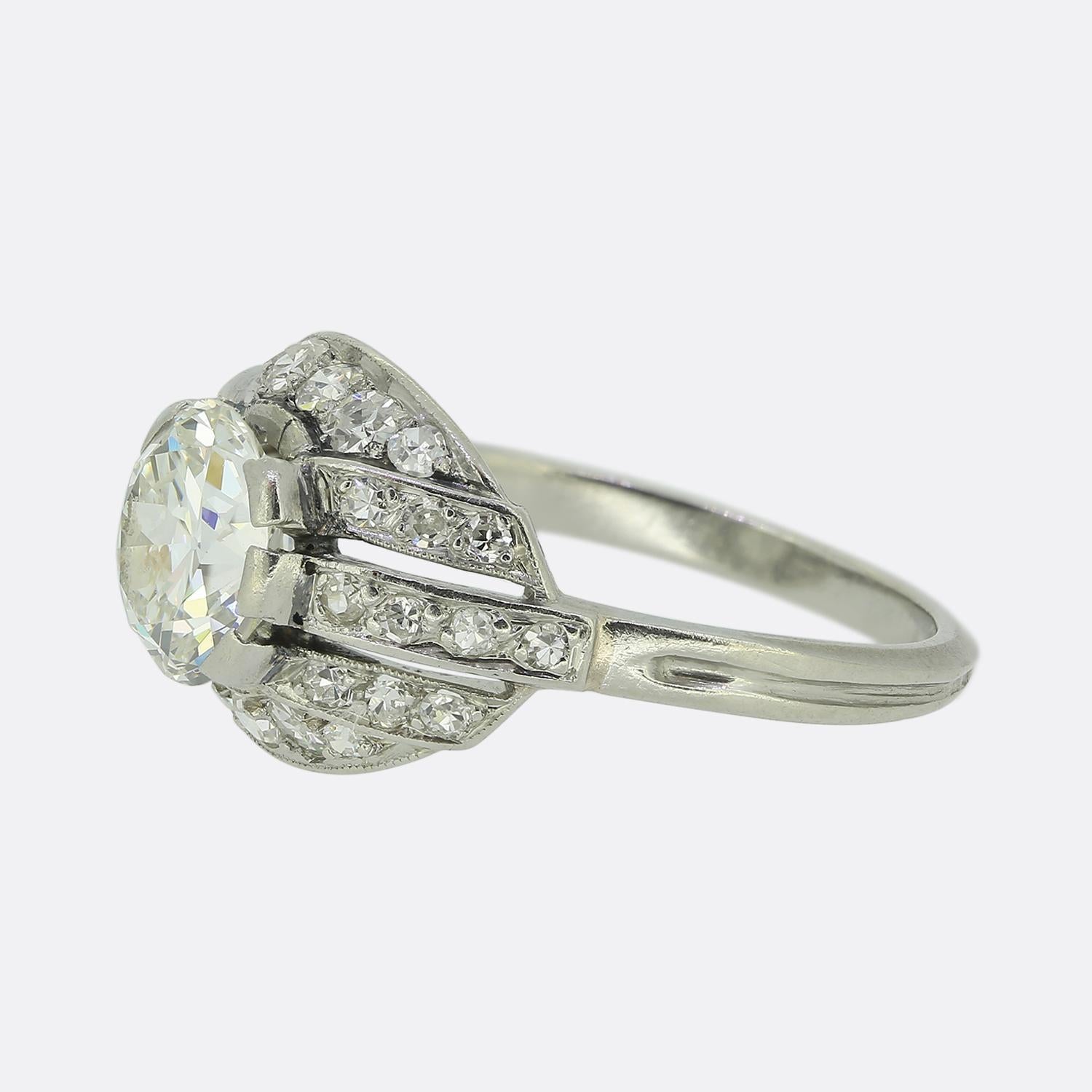 Here we have a delightful Art Deco ring crafted from platinum. At the centre of the face we find captivating round faceted old European-cut diamond, radiating a brilliant white hue. Surrounding this proud central stone is an open domed backdrop