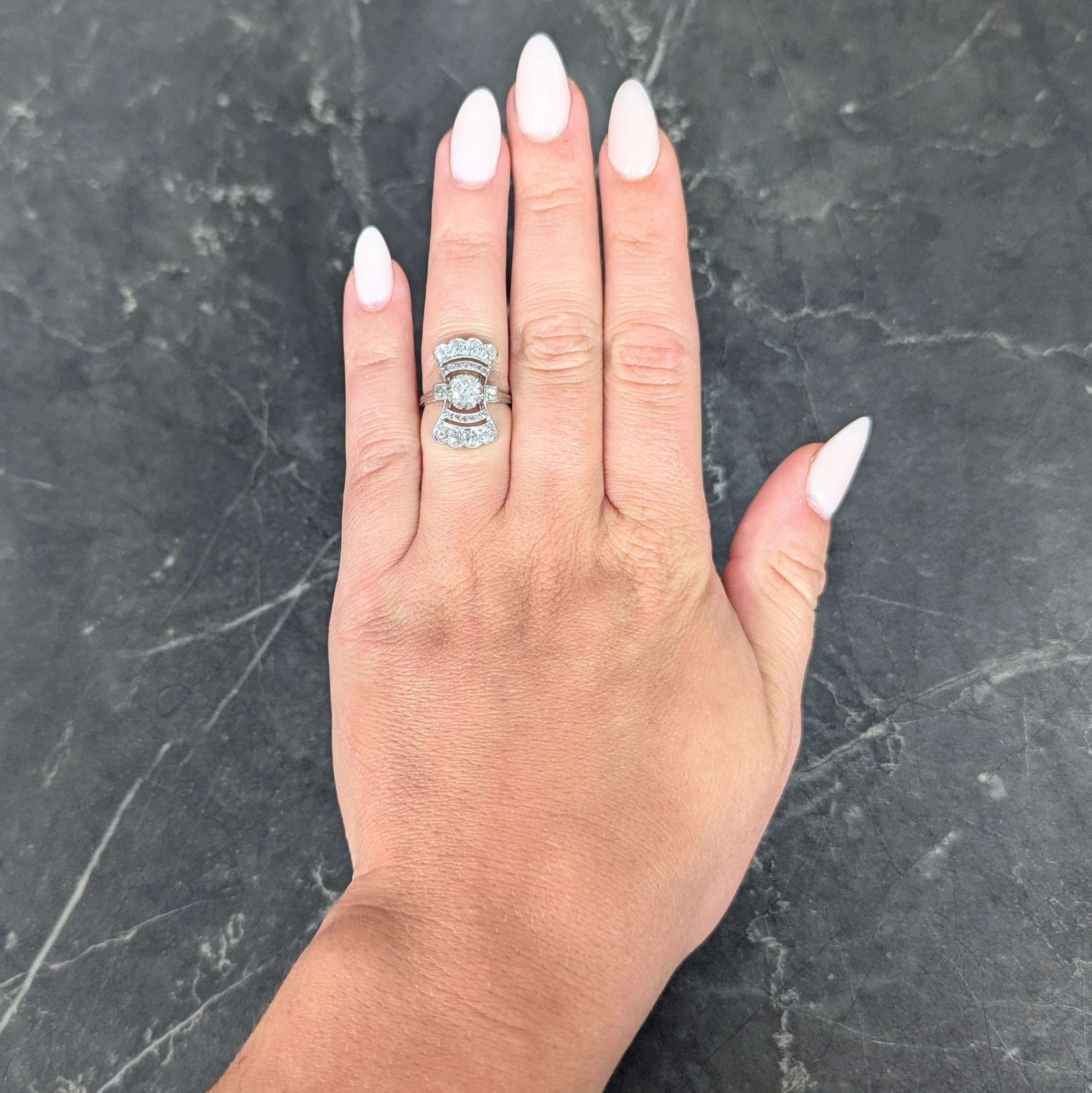 Centering an old mine cut diamond weighing approximately 0.55 carat total - J color with SI1 clarity
Set by talon prongs with a fanning pierced bow-tie motif surround with scalloped edges
Flanked by square form shoulders - bead set with old mine cut
