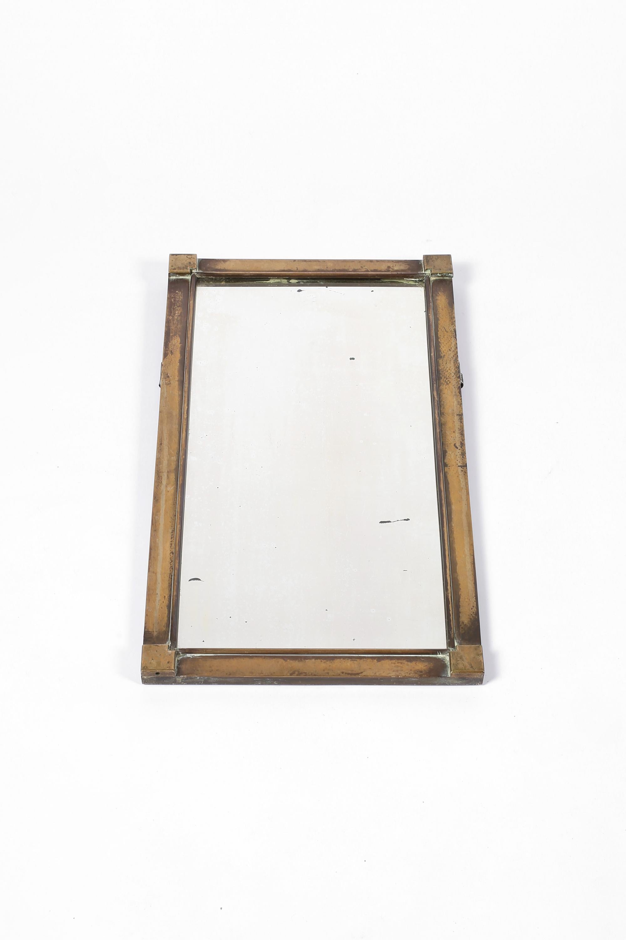 A patinated bronze wall mirror with cubist detailing to the frame. Original mirror plate with attractive subtle foxing and wear. French, c. 1920.
