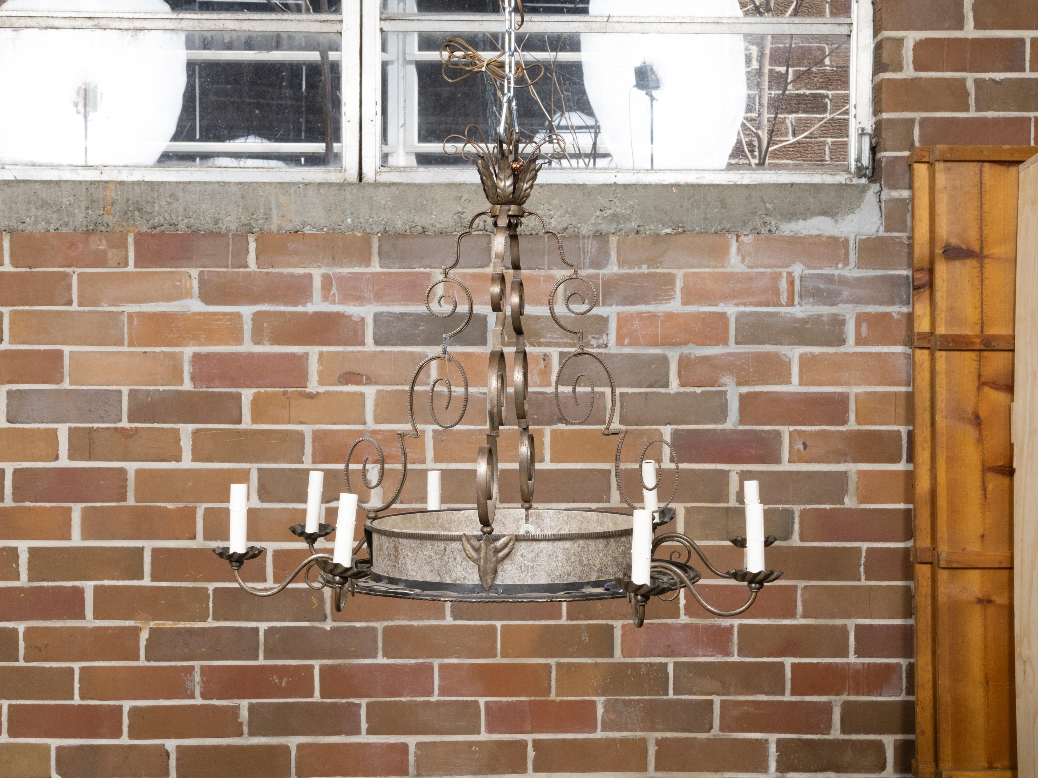 A French Art Deco period wrought iron eight-light chandelier from circa 1920 with large scrolling motifs. This exquisite French Art Deco period chandelier, dating back to circa 1920, showcases the opulence and dynamic design of its era. Crafted from