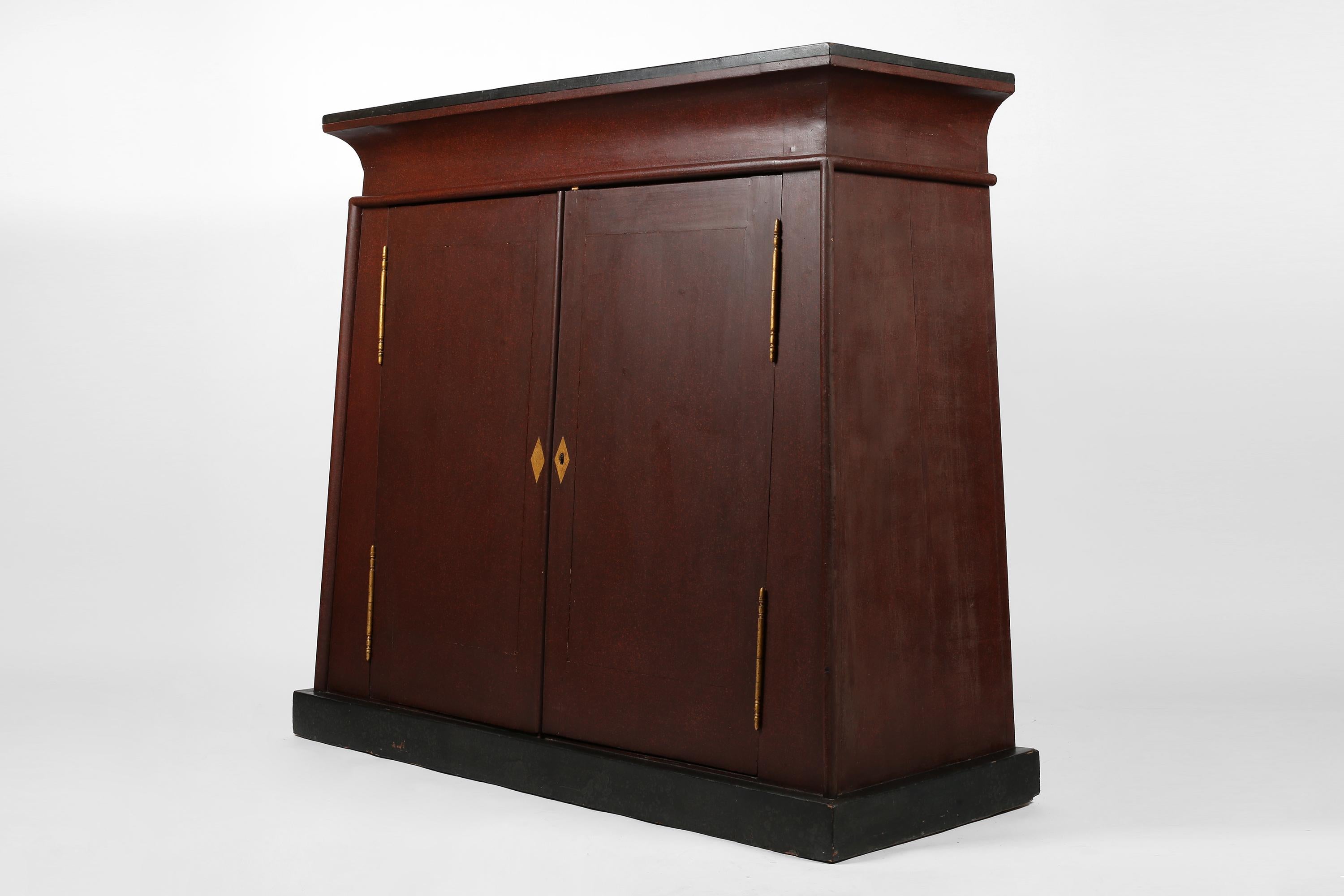 Ein unglaublicher, altägyptisch anmutender Schrank von trapezförmiger Form, der aus dem Château de Castille in der Nähe von Uzès im Gard stammt. Ganz aus massivem Eichenholz gefertigt und lackiert, um Porphyrstein zu simulieren, wobei die Platte und