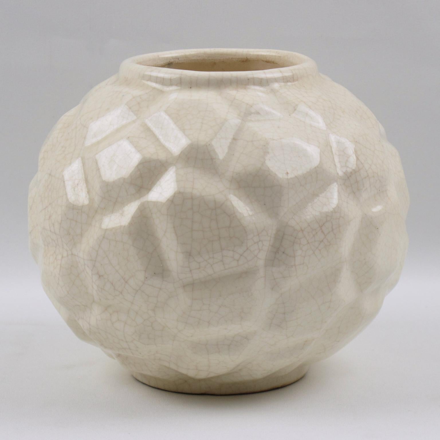 Lovely Art Deco vase by Faience Factory Saint Clement, France. French ceramic vase with white crackle glaze finish. Features a large puffy round shape with large collar opening and detailed stylized carving with geometric shape all around.
The