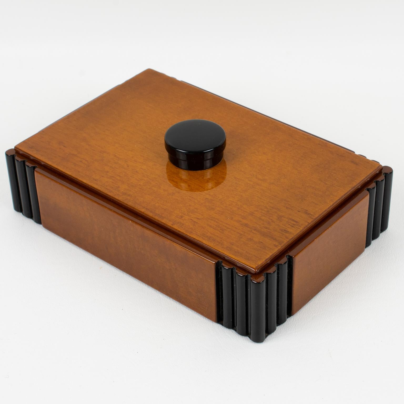 A refined modernist large decorative lidded box. Art Deco typical minimalist rectangular shape with varnish tropical wood and black lacquer carved corners and finial. No visible maker's mark.
Measurements: 7.69 in. wide (19.5 cm) x 5.13 in. deep (13