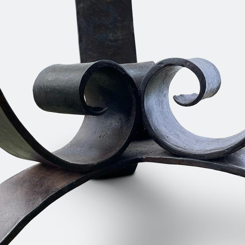 Elégante table basse en fer forgé de style Art déco français des années 1940. 
D'une simplicité discrète, cette pièce a été forgée avec une grande précision. L'intérieur de chacune des volutes est martelé à la main. Reposant sur trois  Avec ses
