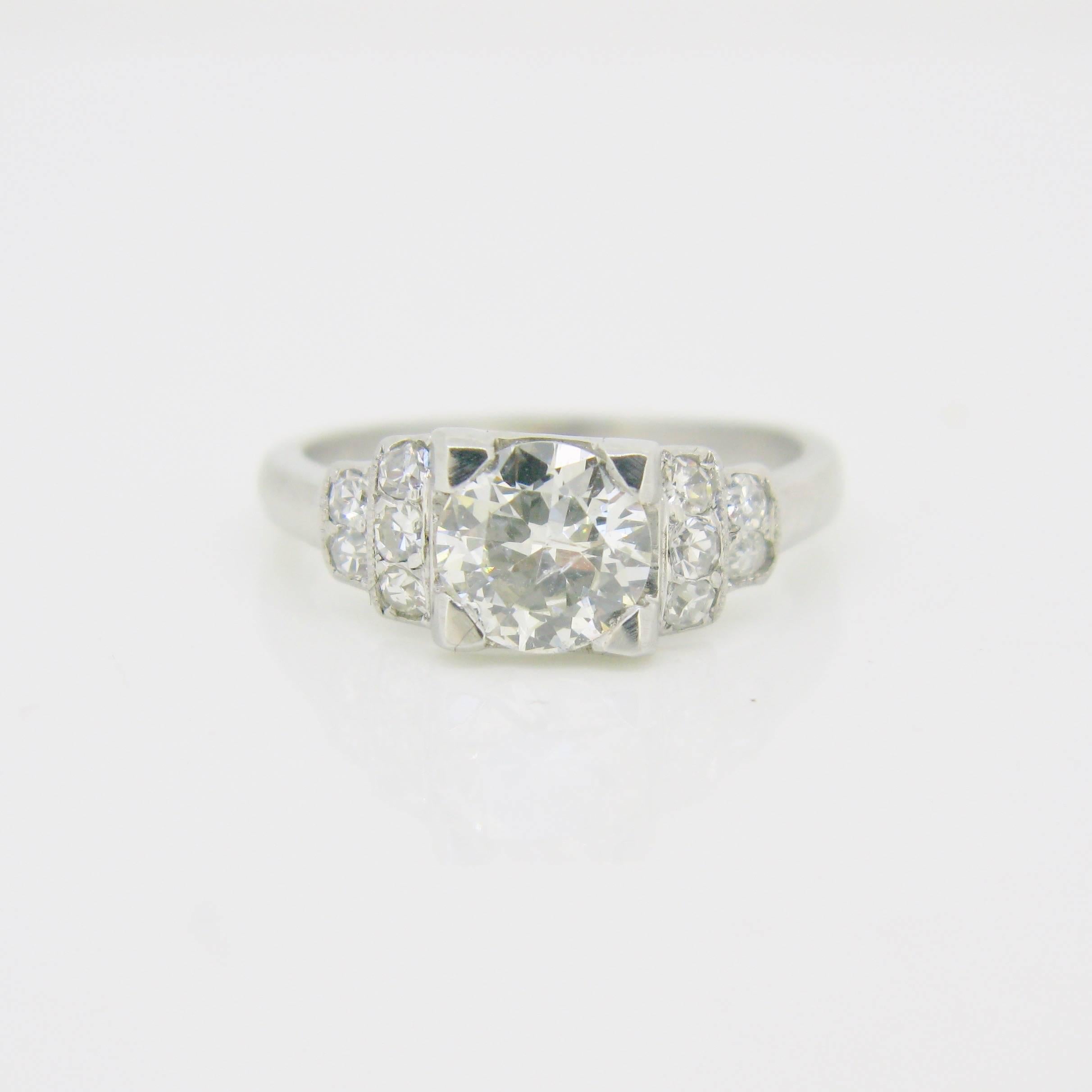 This lovely platinum ring features a stunning brilliant cut diamond weighing approximately 1ct (color I, clarity SI). It is framed by 5 diamonds on each side for a total weight of approximately 0,25ct. The diamonds are set securely by 4 prongs and