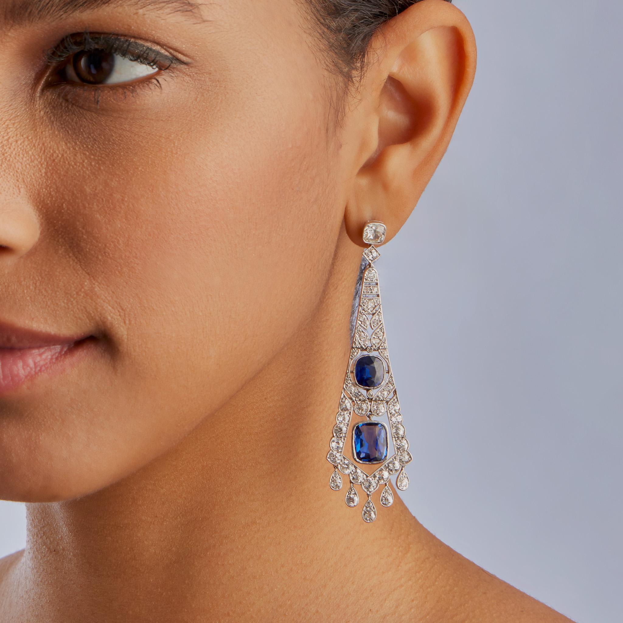 Created in France circa 1920, these Art Deco platinum pendant earrings are set with approximately 13.00 carats of sapphires and 7.00 carats of diamonds. Each pendant earring is designed as a cushion-cut diamond top suspending an articulated cascade