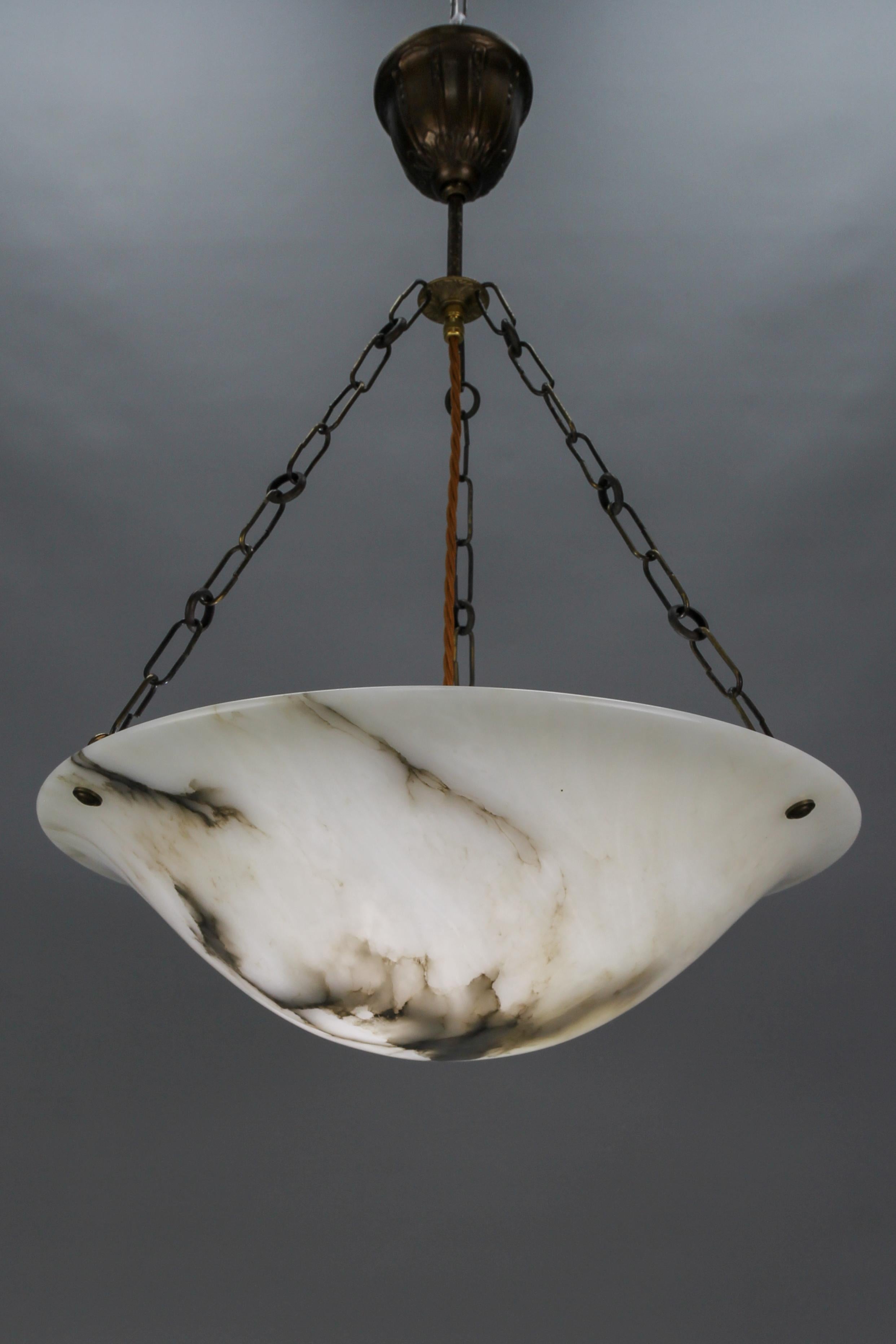 Antique French Art Deco black veined white alabaster pendant light fixture.
An elegant and large alabaster pendant ceiling light fixture from circa 1920. The beautifully veined white alabaster bowl is suspended by three chains.
The light shining