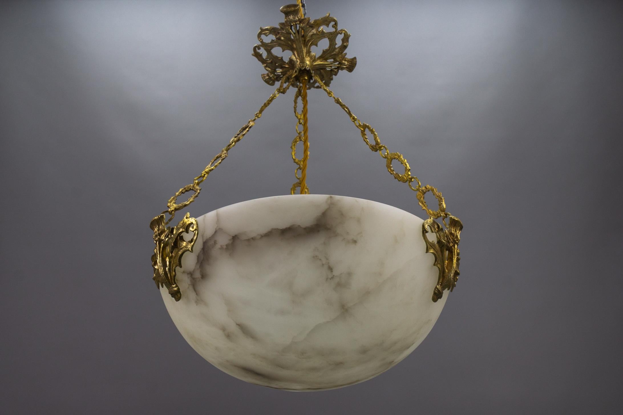 Art Deco white and black veined alabaster pendant light fixture.
A wonderful alabaster pendant ceiling light fixture from circa the 1920s. Beautifully veined and masterfully carved white alabaster bowl suspended by three decorative bronze chains,
