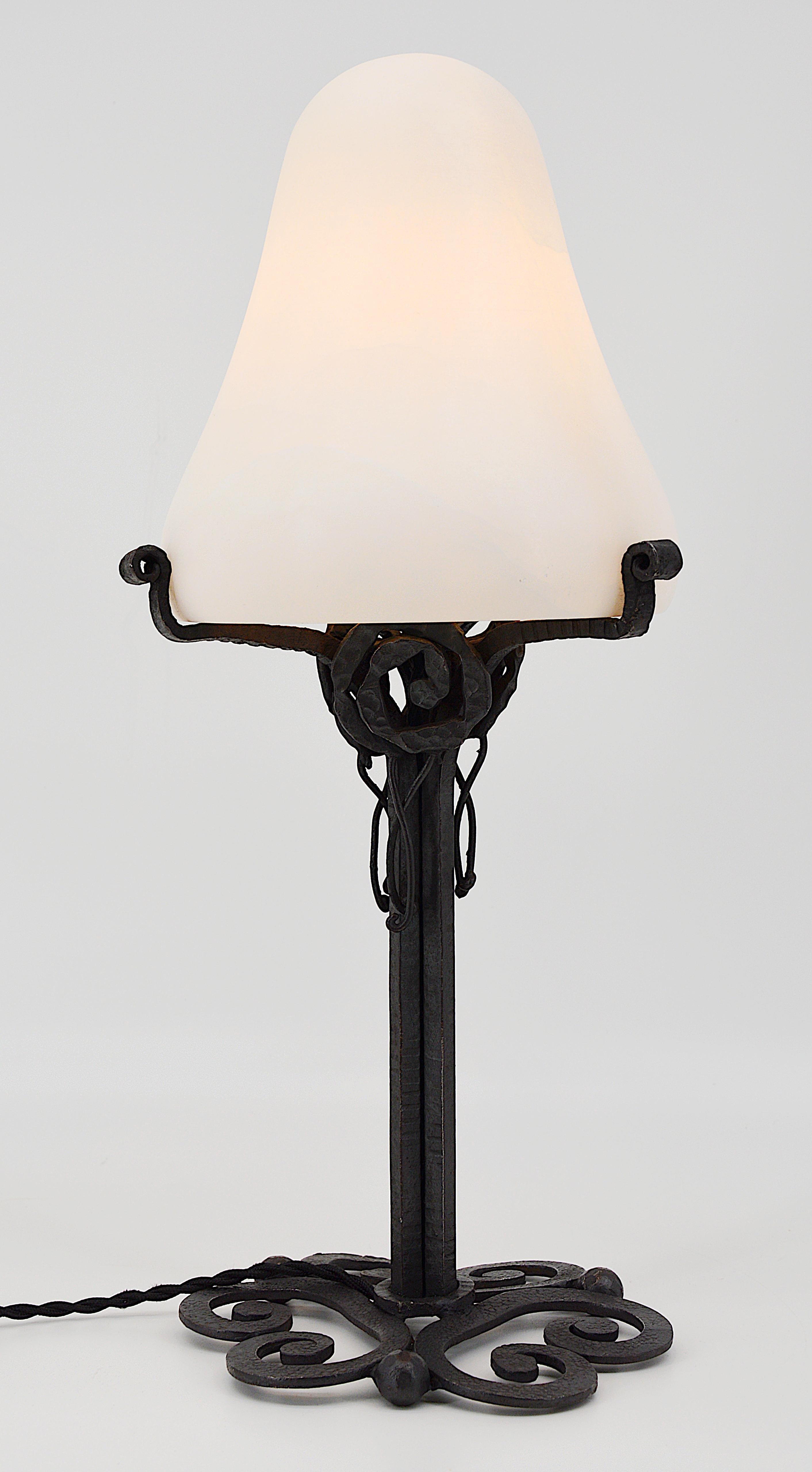 French Art Deco table lamp, France, circa 1925. Thick alabaster shade on its stunning wrought iron base. Close to Edgar Brandt's works. Old alabaster cannot be compared to new ones. Old alabaster has veins. Sometimes they can be mistaken for cracks.