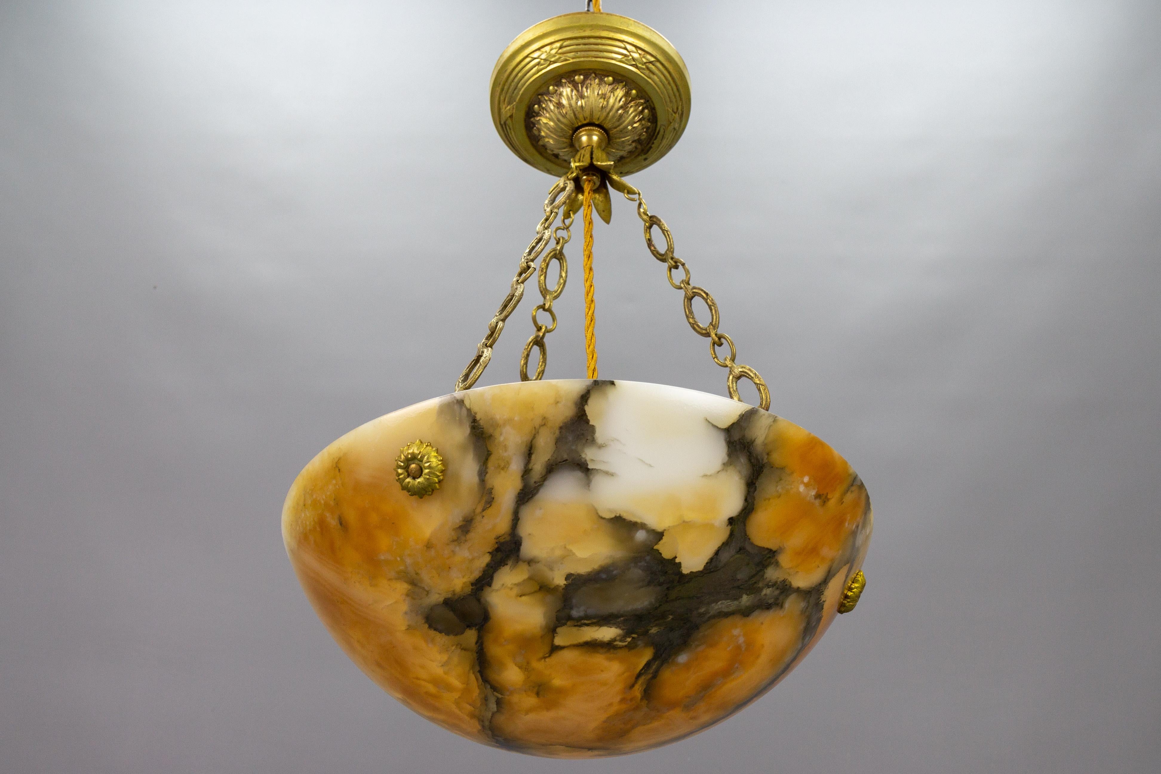 An adorable French pendant light featuring an alabaster shade in a lovely, light and dark, orange hue with black and cream veining. The lampshade - bowl is suspended from three ornate brass chains, which attach to the dome with finely made