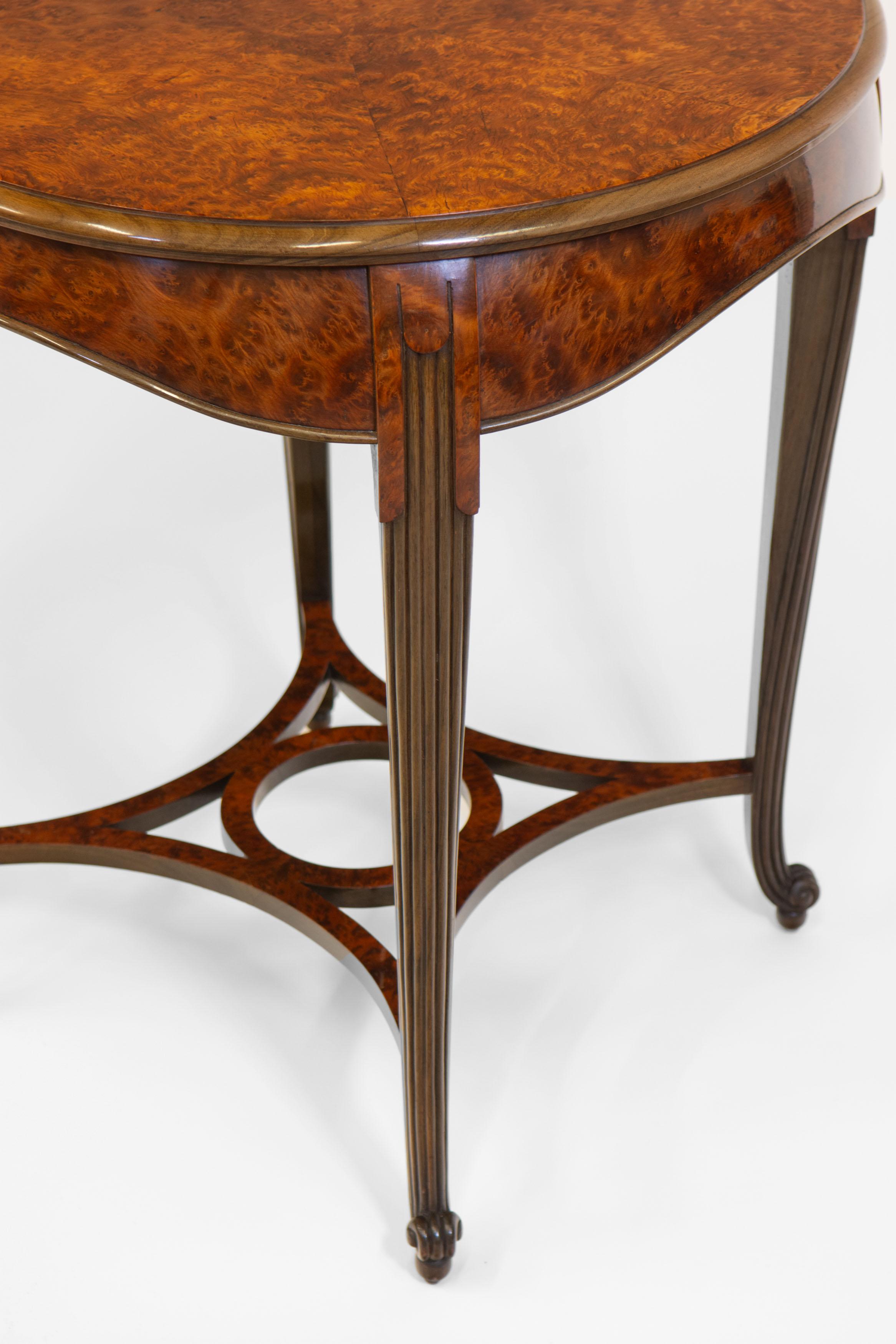  A superb French Art Deco amboyna occasional side table. Circa 1930.

This elegant table has a shaped cushion frieze, standing on walnut reeded legs. It terminates to an outswept scroll and ball foot, joined by a central stretcher of circular form.