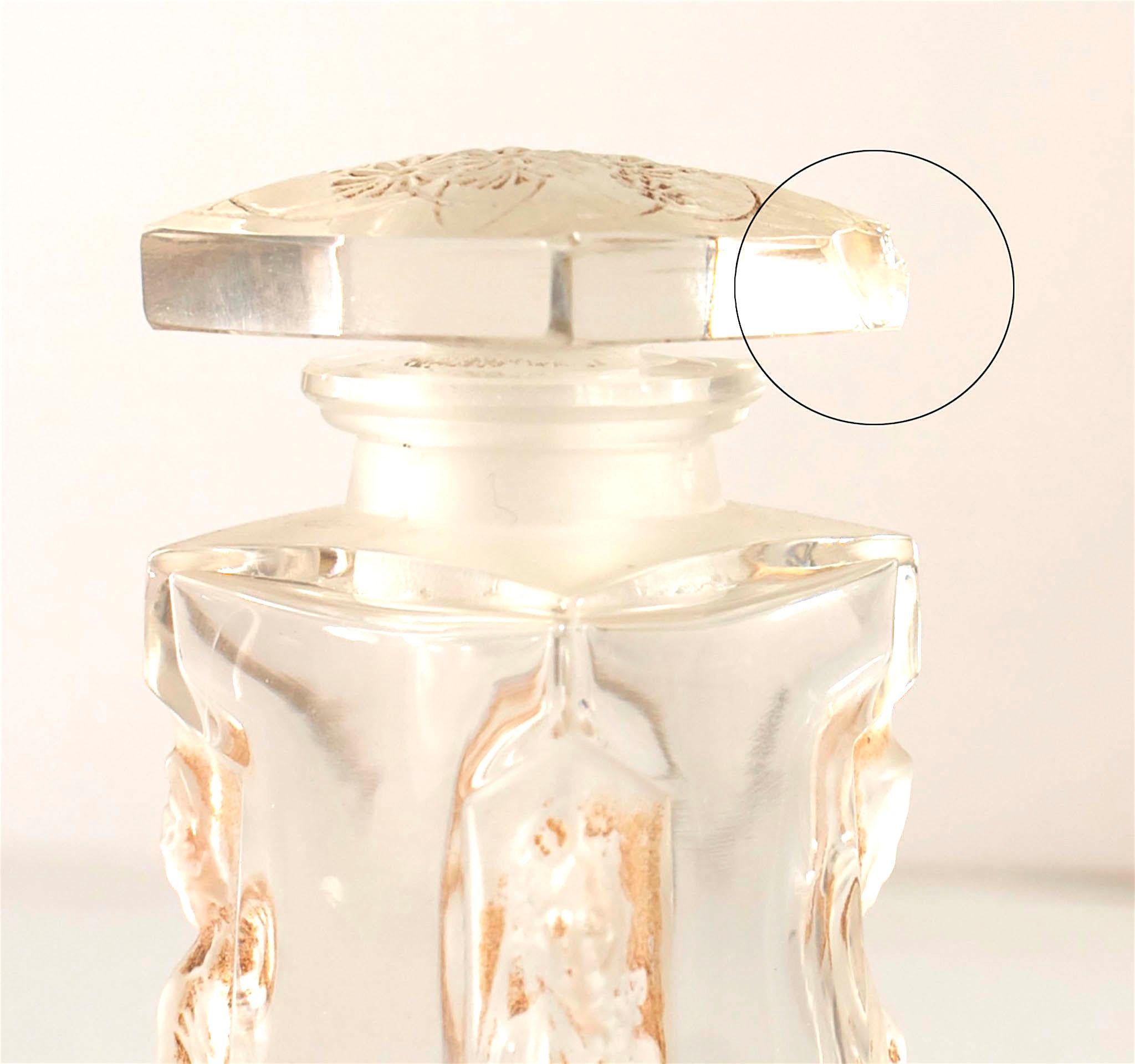 Bottiglia di profumo francese in vetro trasparente (AMBRE D'ORSAY by D'ORSAY), decorata con figure di donne vestite incassate ai quattro angoli, sotto un tappo quadrato con fiori dentellati (firmata Lalique) (AS IS- scheggiatura sul tappo)