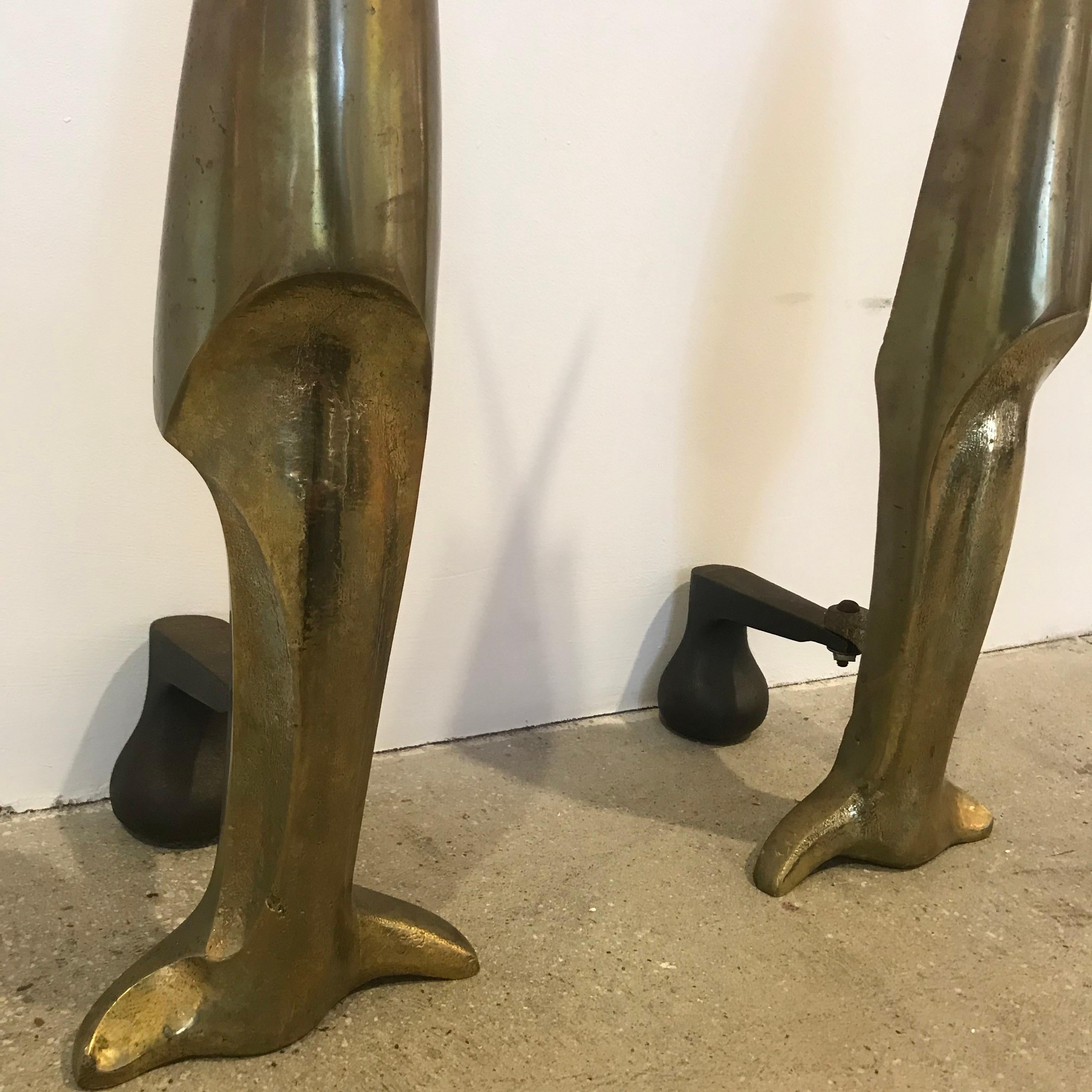 A pair of stylized bronze flame aged bronze andirons attributed to Pierre Legrain. Attached to iron backs. An similar example sold at Sotheby’s sale 3944.